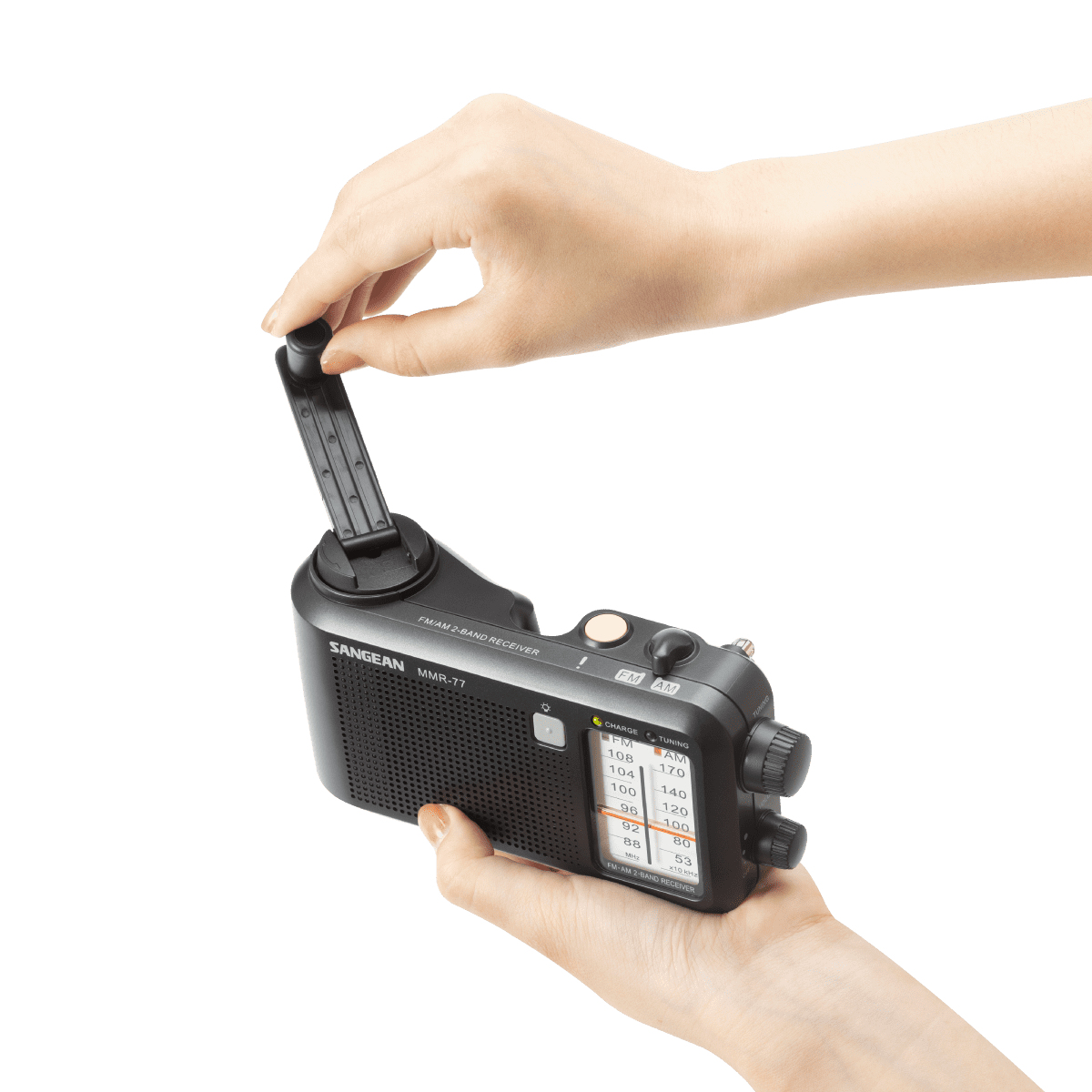 Dłonie regulują czarno-szare przenośne radio na białym tle.