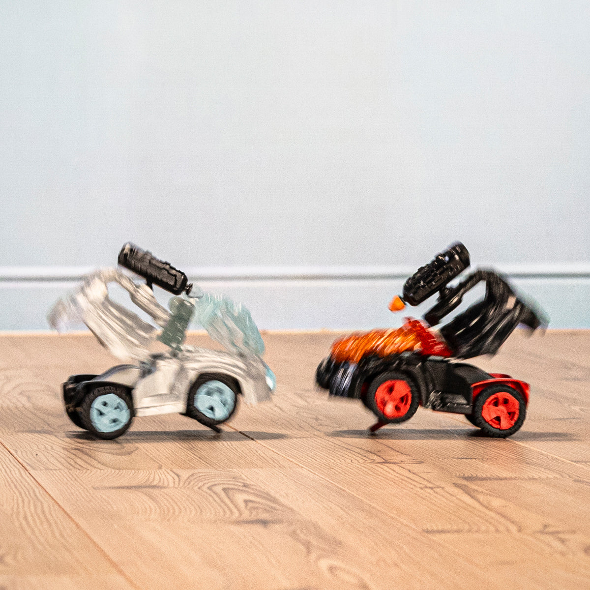 Zwei Spielzeugautos stoßen zusammen. Ein Auto ist silberfarben. Das andere ist orangefarben.