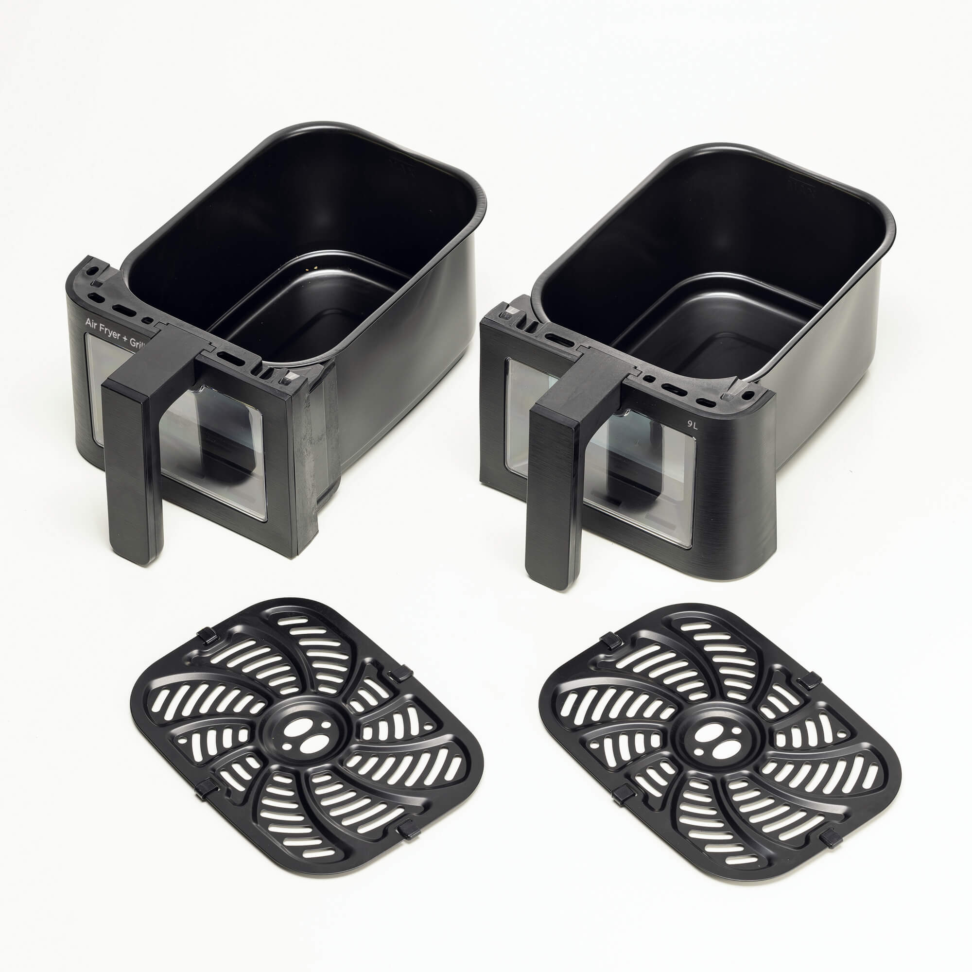 Dwa czarne kosze do frytkownicy powietrznej i dwie czarne kratki na białym tle.
