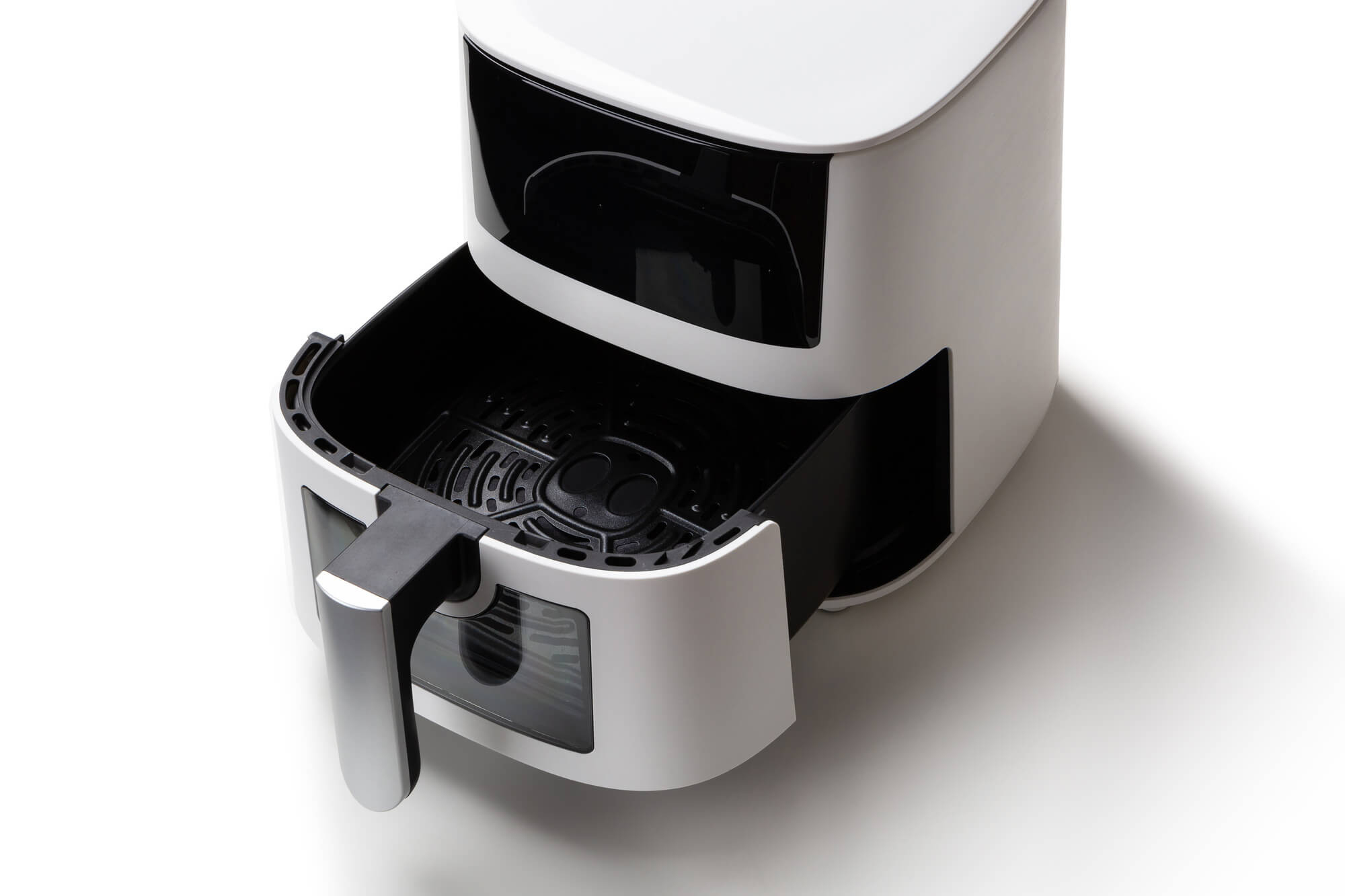 Biała frytownica powietrzna z otwartą szufladą na białej powierzchni.