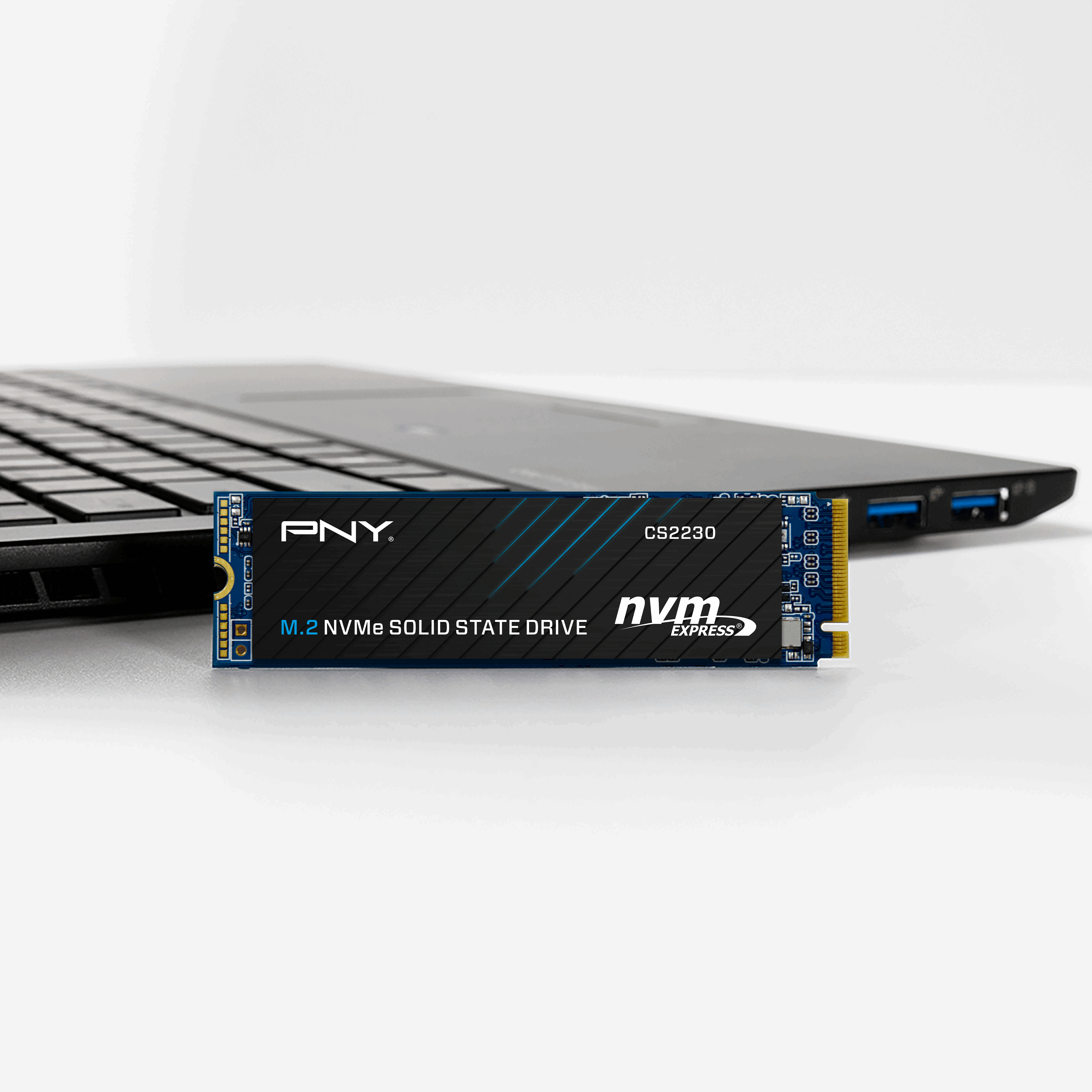 PNY M.2 NVMe SSD na laptopie. Dysk SSD, czarny z niebieskim wzorem i białym tłem.