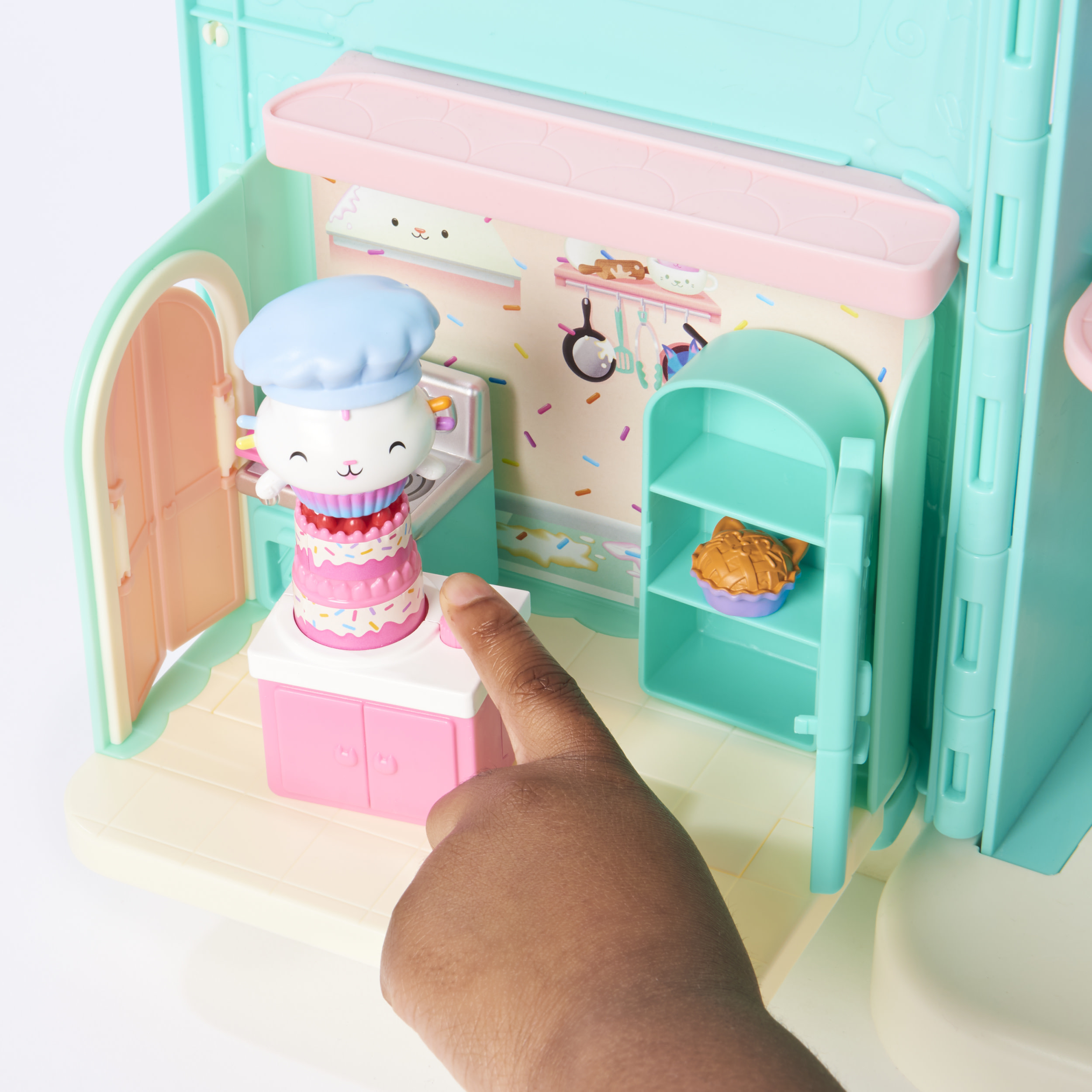 Ein Spielzeugküchenset mit einer Kochfigur und einer Hand, die auf einen Schrank zeigt.
