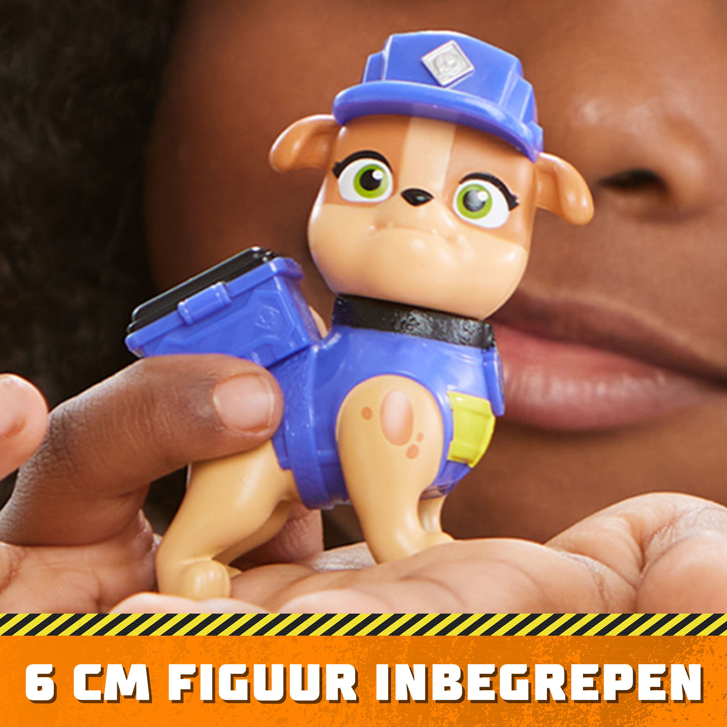 Eine Kinderhand hält eine Paw Patrol-Spielfigur eines Hundes in blauer Uniform.
