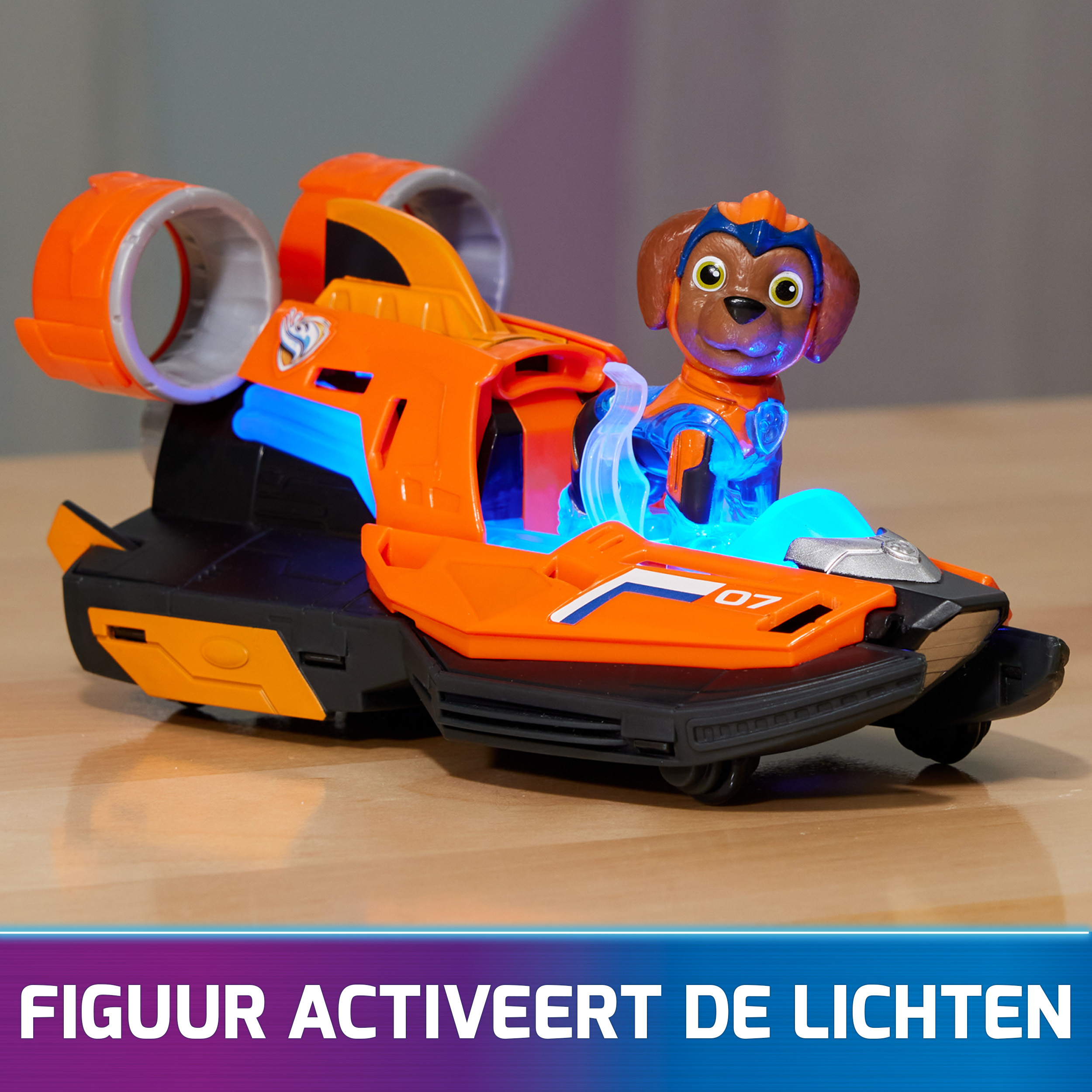 Orangenes Spielzeugboot mit einer Hundefigur. Es hat blaue Lichter. Unten steht "FIGUUR ACTIVEERT DE LICHTEN".