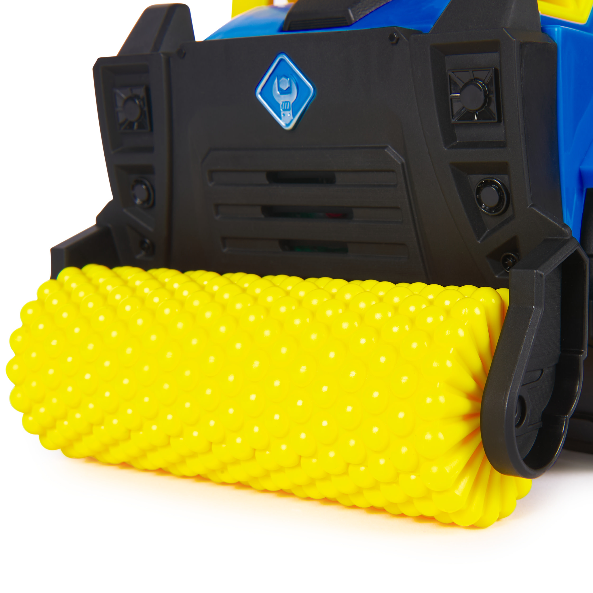 Gelbe Spielzeugbürste an einem blau-schwarzen Spielzeugfahrzeug, weißer Hintergrund.