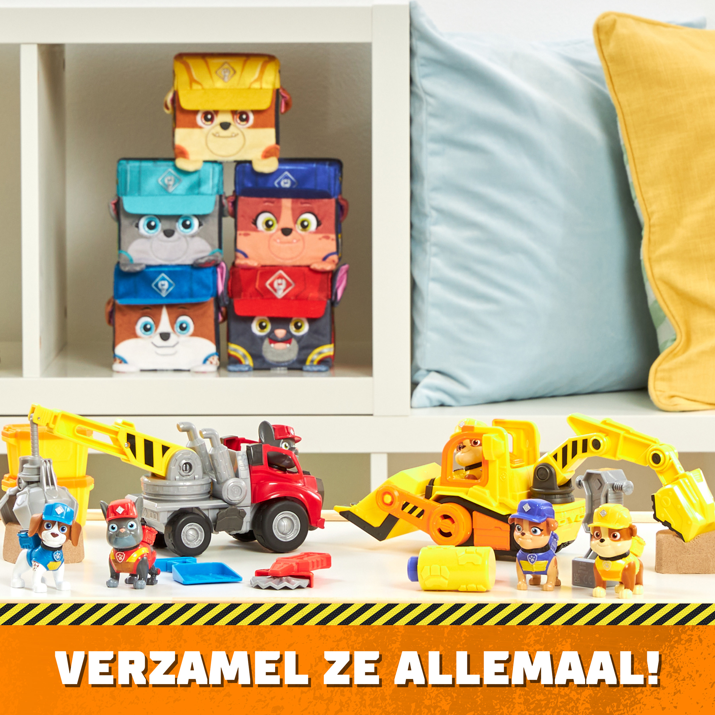 Spielzeug-Bausatz mit Figuren und Spielzeugwürfeln. Ein Regal und ein blaues Kissen im Hintergrund. "VERZAMEL ZE ALLEMAAL!".