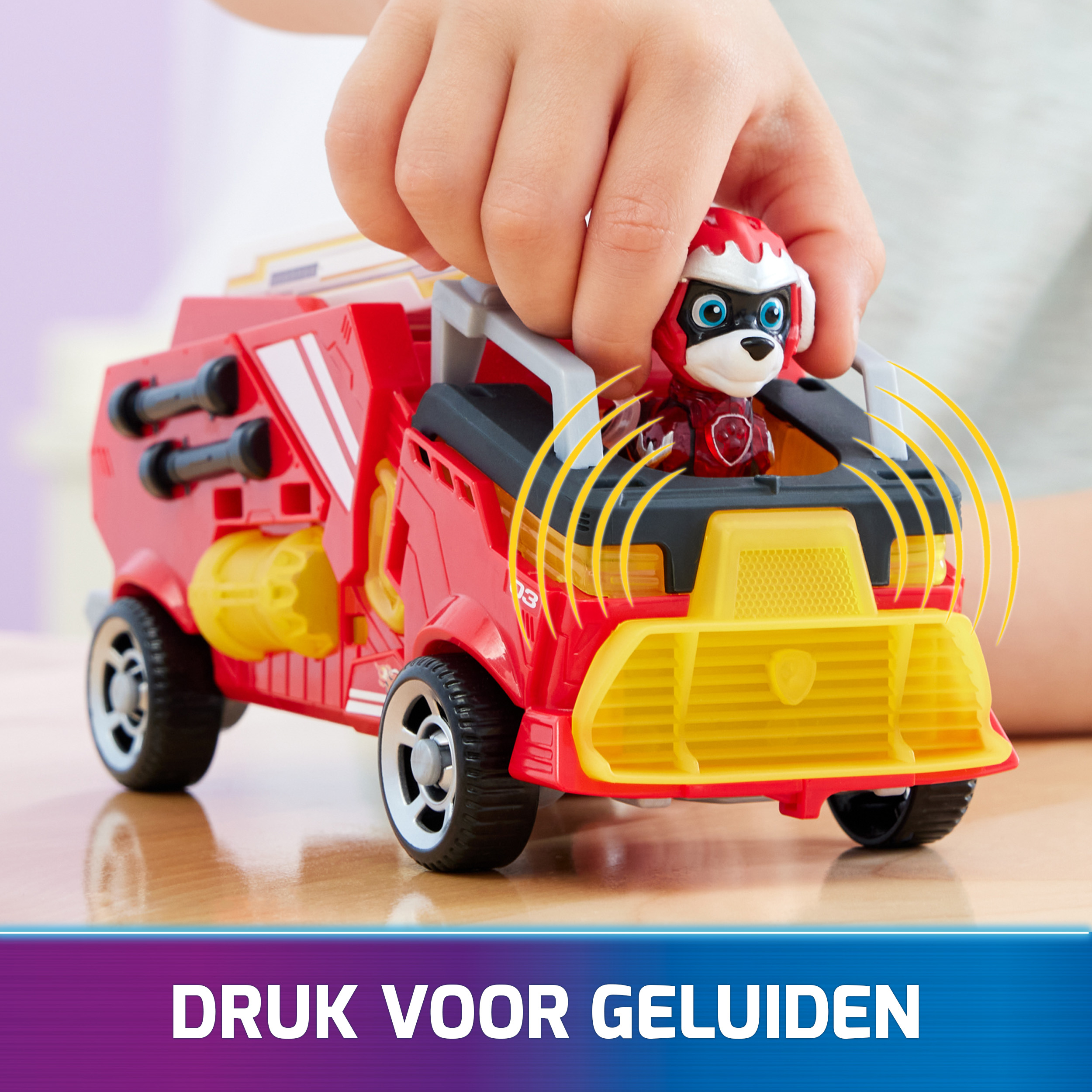 Kinderhand interagiert mit rotem/gelbem Spielzeuglaster mit Paw Patrol Figur.