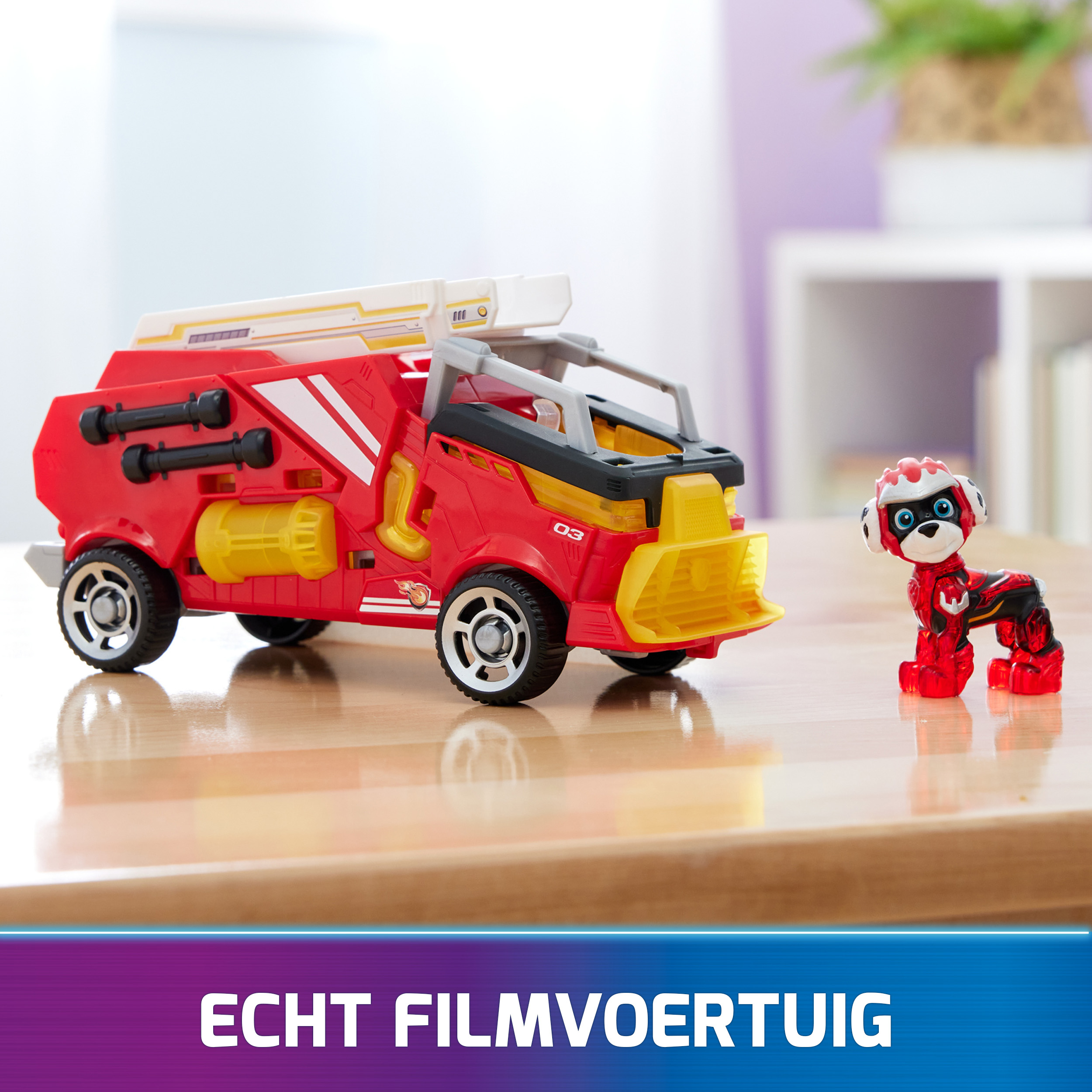 Roter Spielzeug-Feuerwehrwagen und eine kleine Hundefigur auf Holz. Hintergrund ist ein Regal und eine Pflanze.