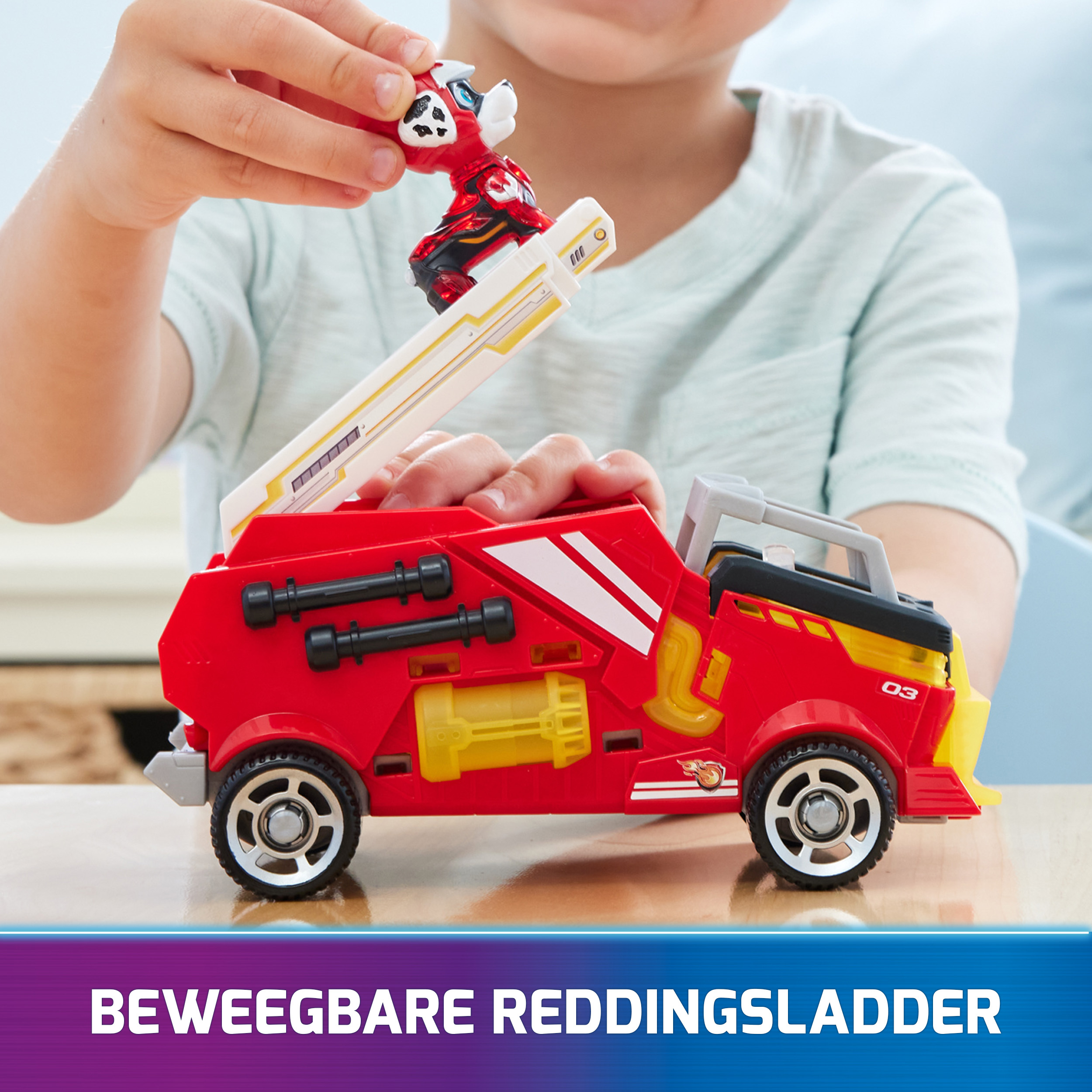 Ein Kind spielt mit einem roten Spielzeug-Feuerwehrauto und einem Spielzeug-Feuerwehrmann auf weißer Oberfläche.