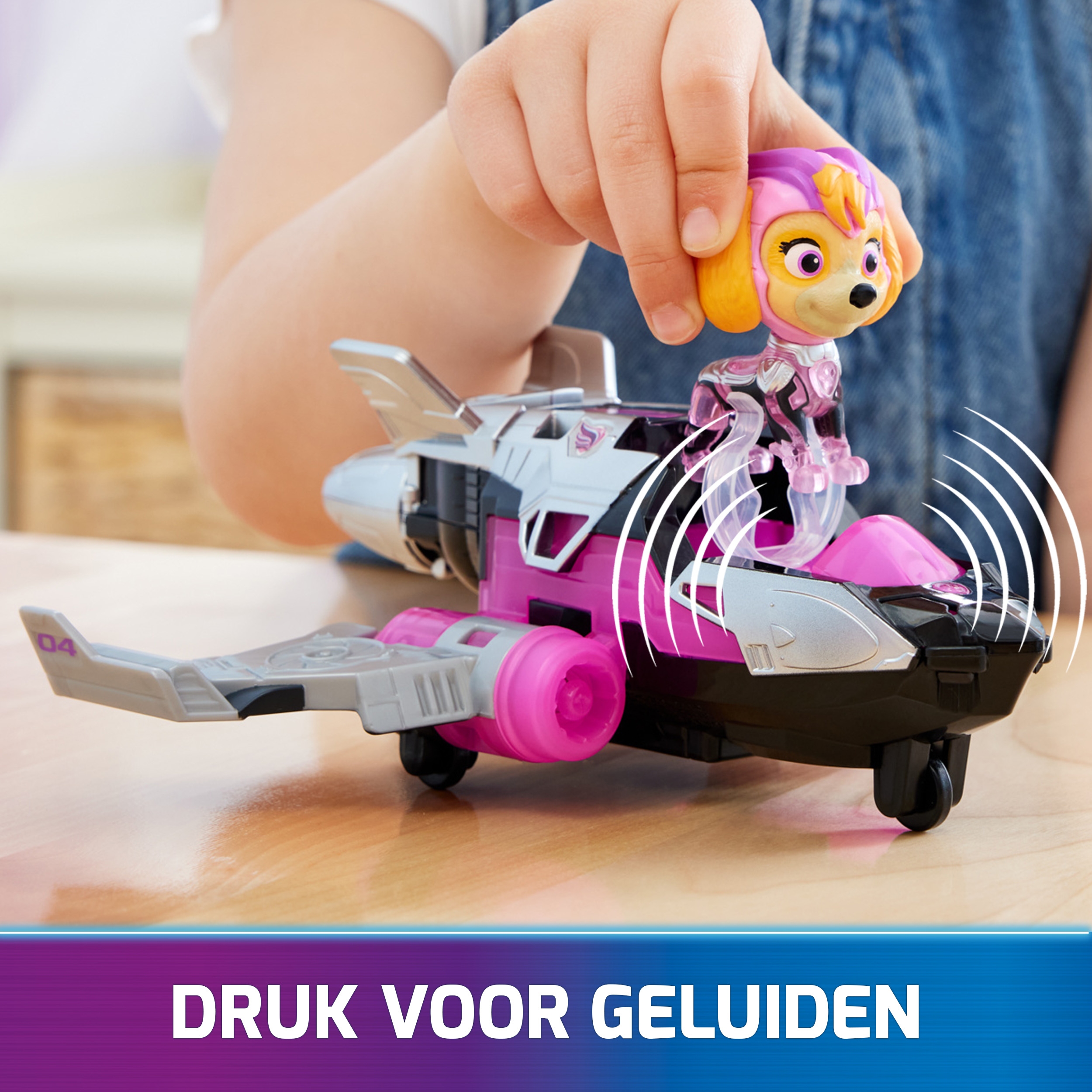 Ręka dziecka z zabawką samolotem i postacią z Psiego Patrolu. Tekst: DRUK VOOR GELUIDEN (Naciśnij, aby uzyskać dźwięki).