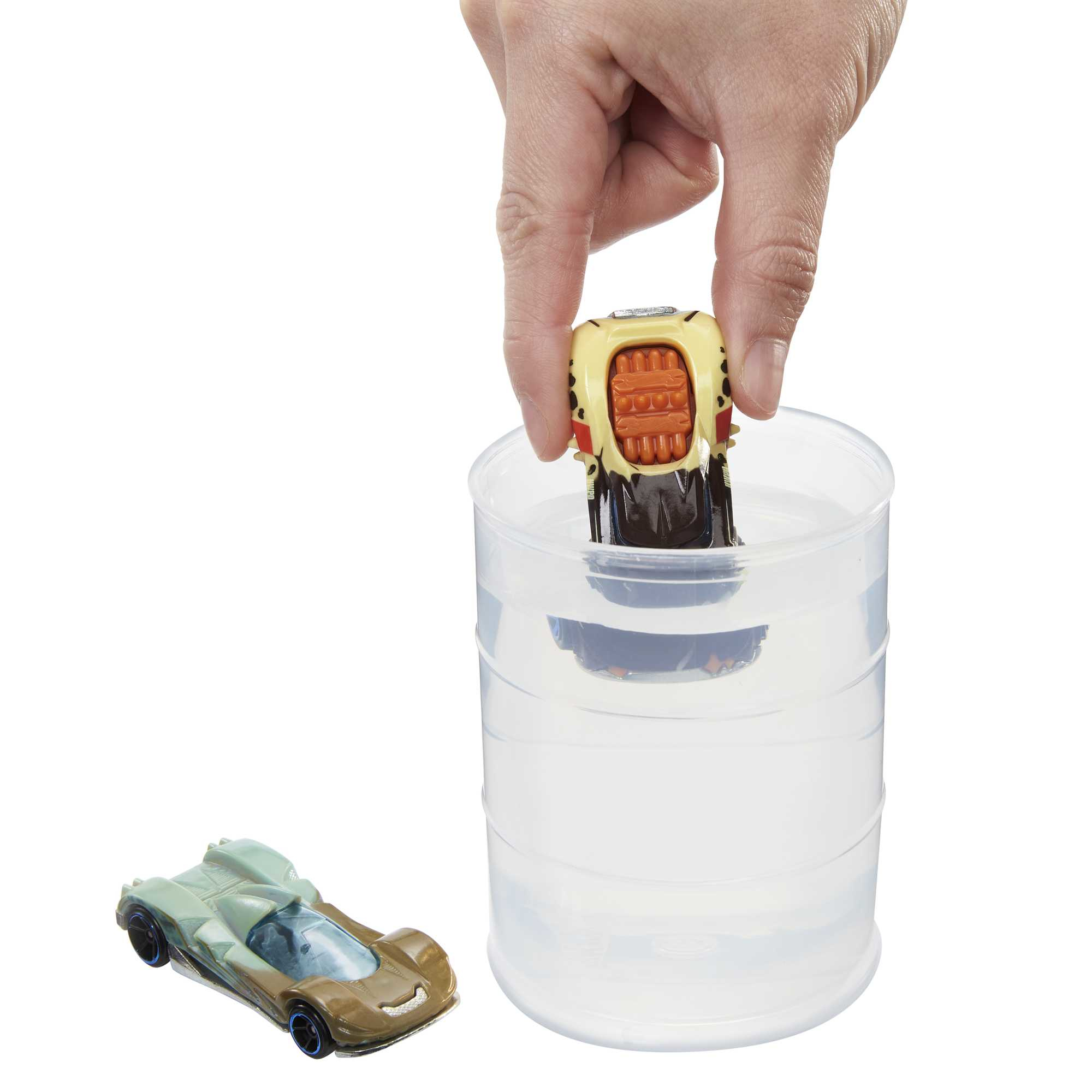 Ręka zanurza samochodzik w wodzie; w pobliżu znajduje się inny samochód.