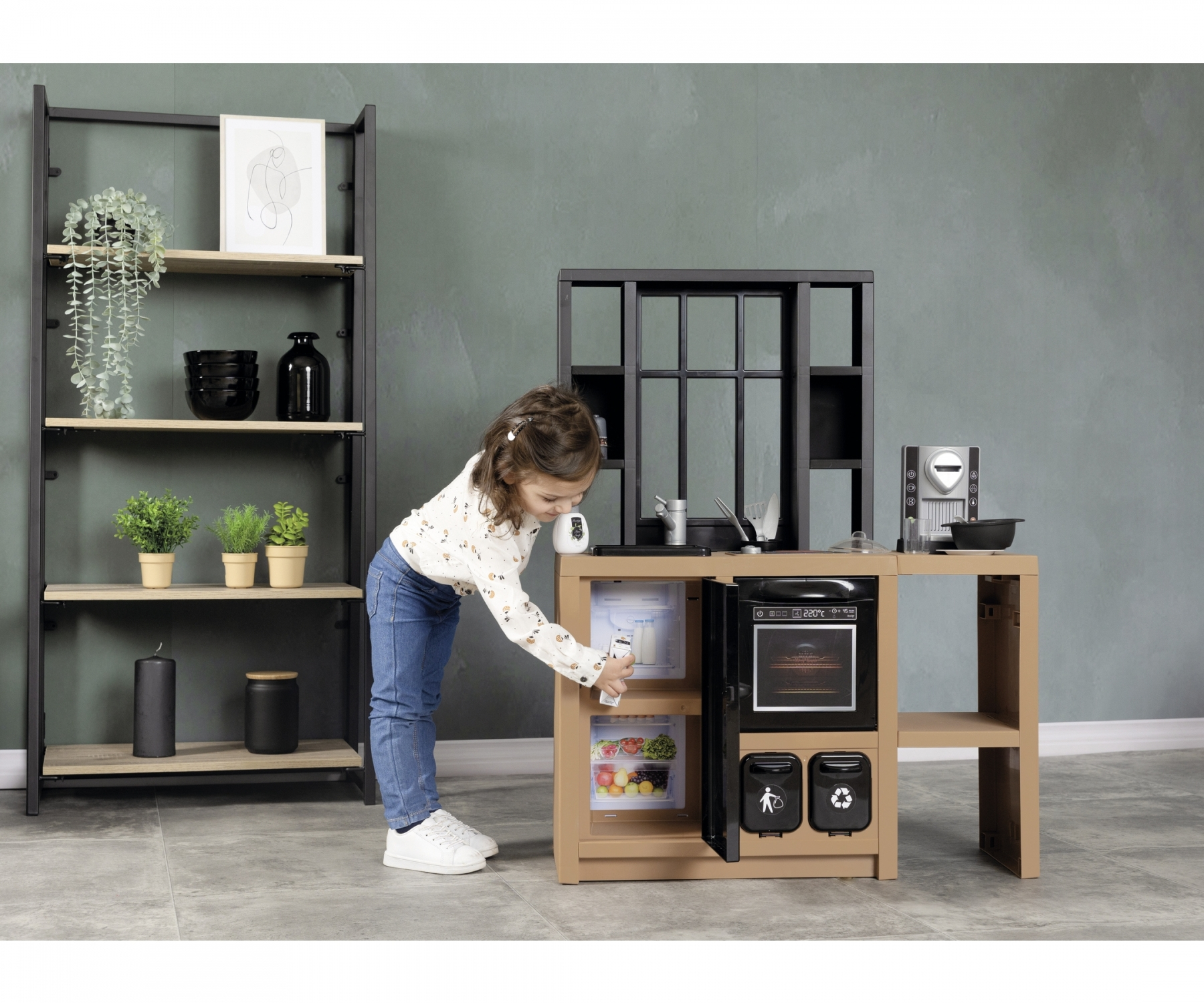 Dziecko bawi się zabawką kuchenną. Są półki i ściana.