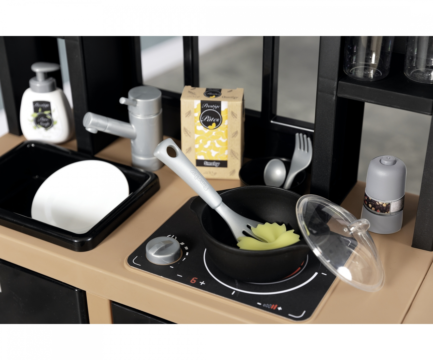 Zestaw zabawek kuchennych z czarnymi szafkami, kuchenką i różnymi przyborami. Widoczne jedzenie.