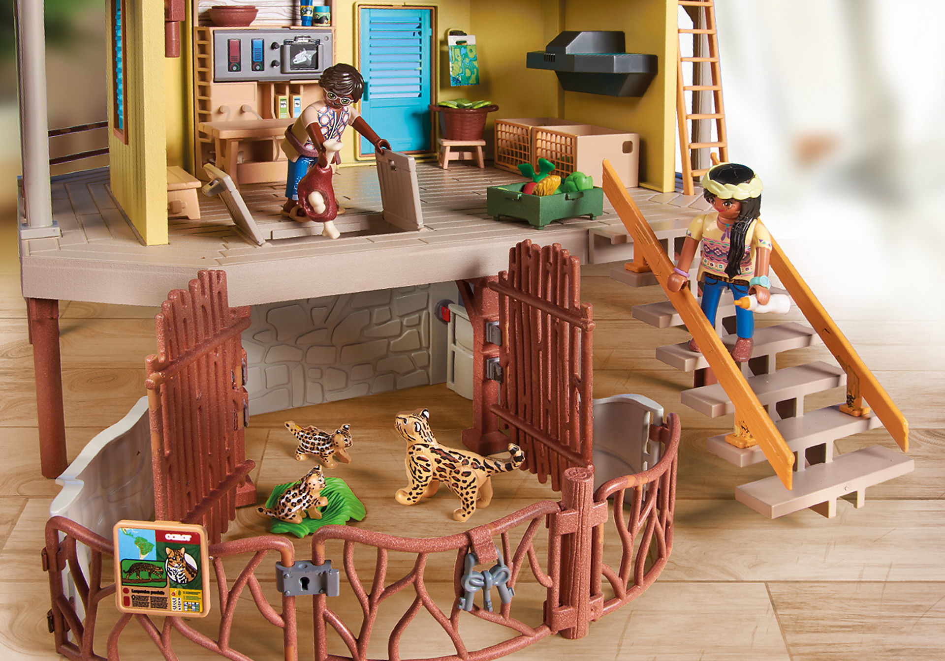 Playmobil-Spielset. Menschen und Tierfiguren in einem zweistöckigen Gebäude. Holzzaun umgibt ein Gehege.