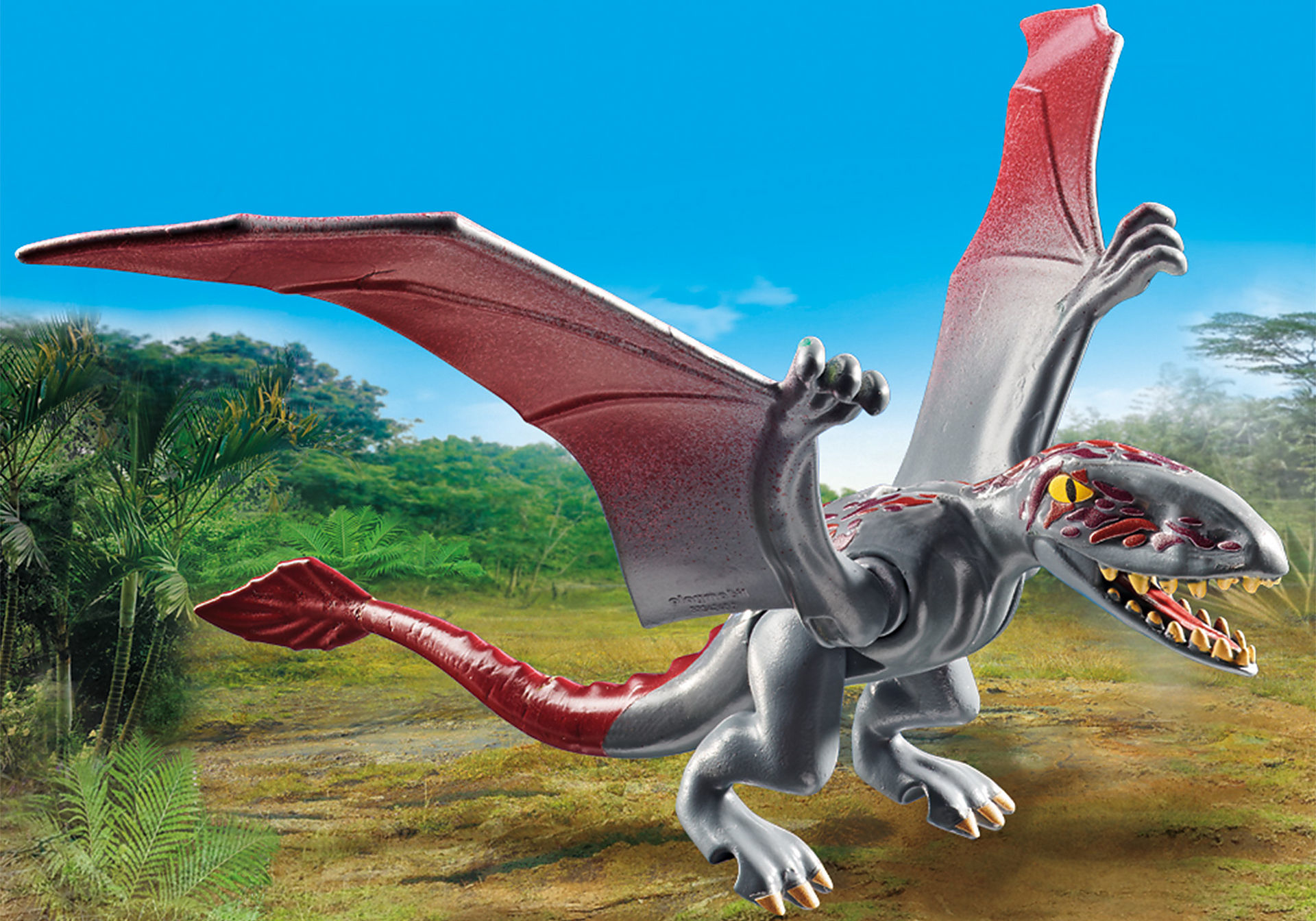 Pterodattilo giocattolo grigio con ali rosse. Lo sfondo presenta una giungla e un cielo blu.