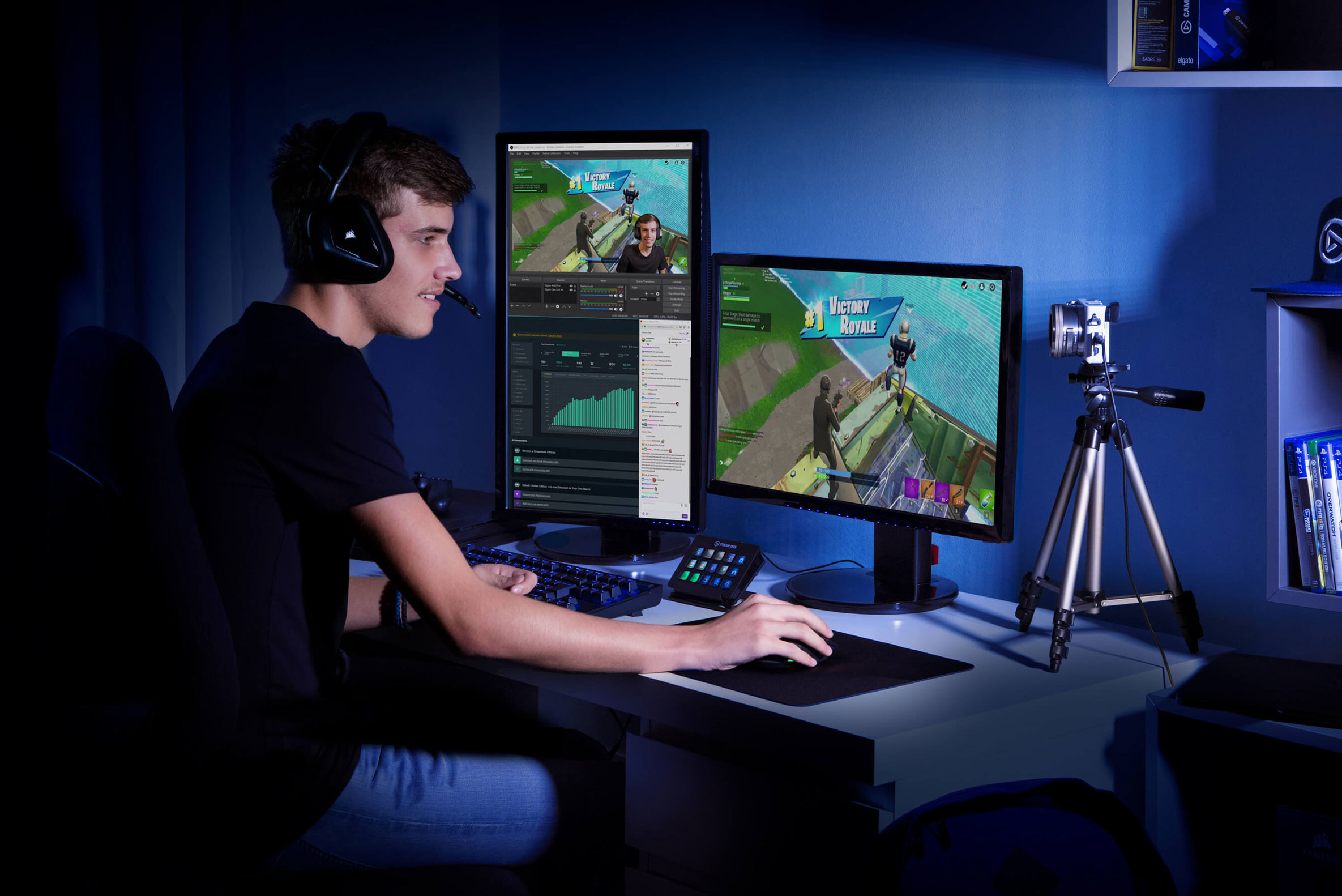 Mężczyzna gra, z dwoma monitorami i kamerą ustawioną na biurku.