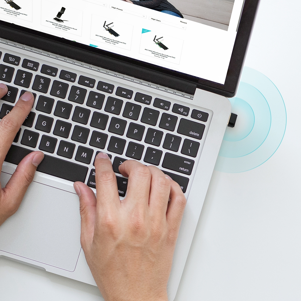 Laptop z podłączonym kluczem USB. Ręce piszą na klawiaturze i wyświetlany jest sygnał bezprzewodowy.