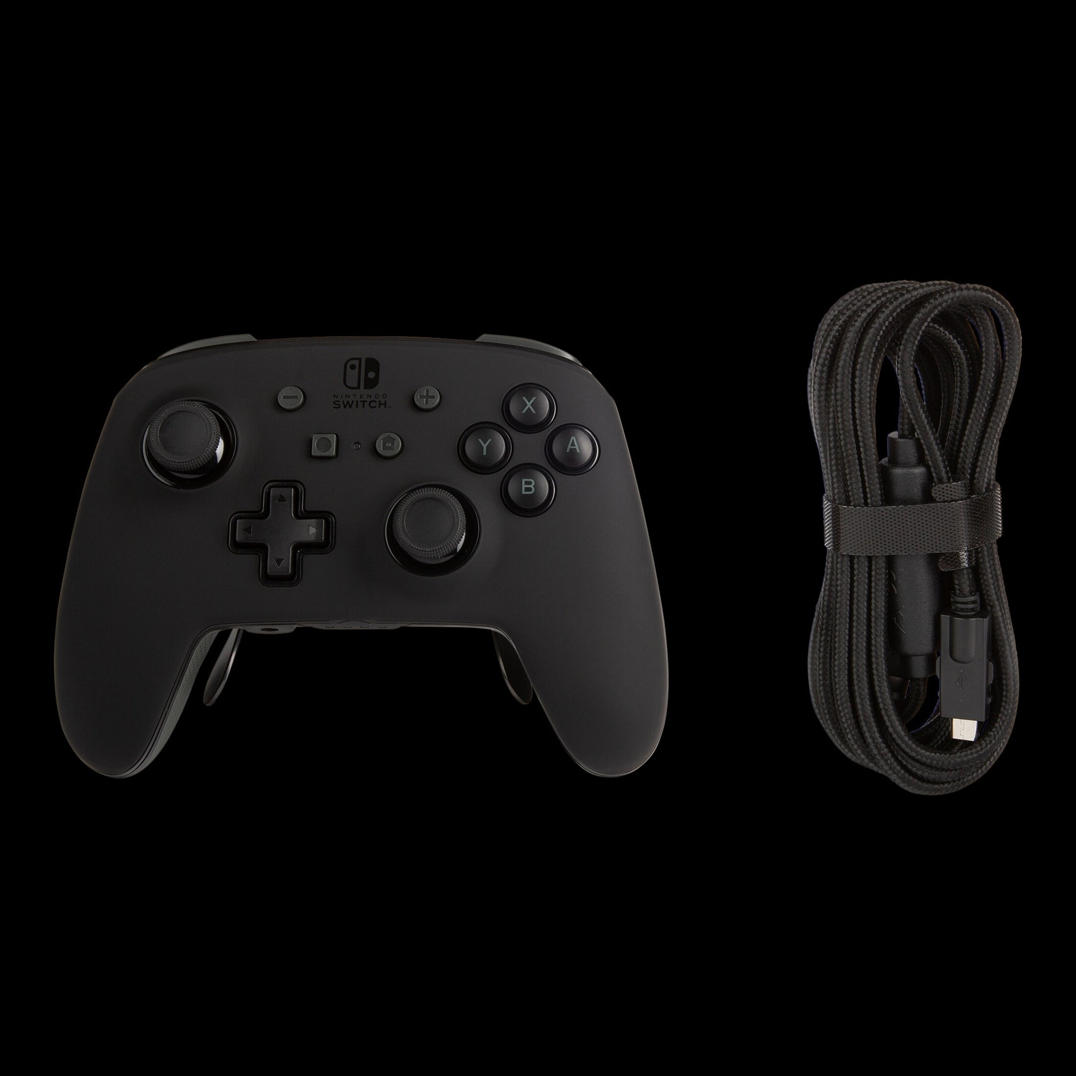 Black Nintendo Switch Pro Controller and a black charging cable on black background.