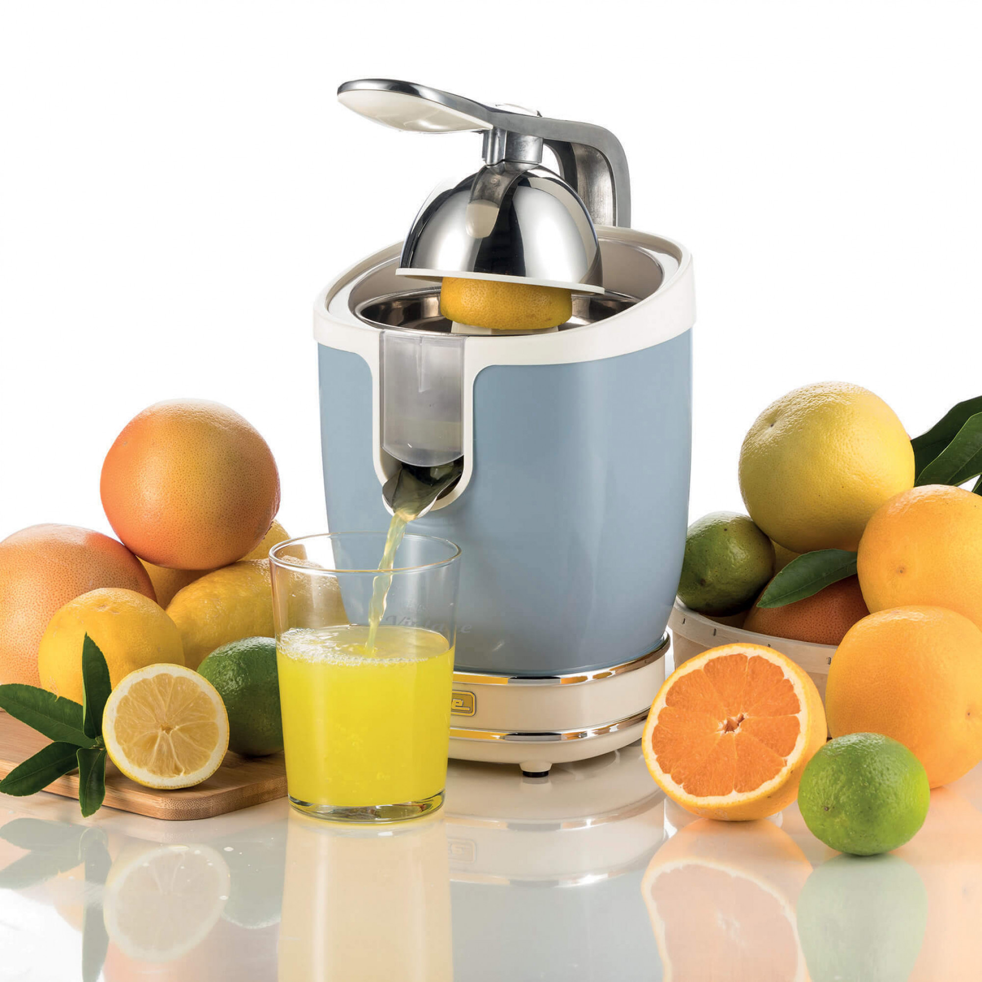 Zitruspresse mit Orangen und Zitronen. Saft fließt ins Glas.