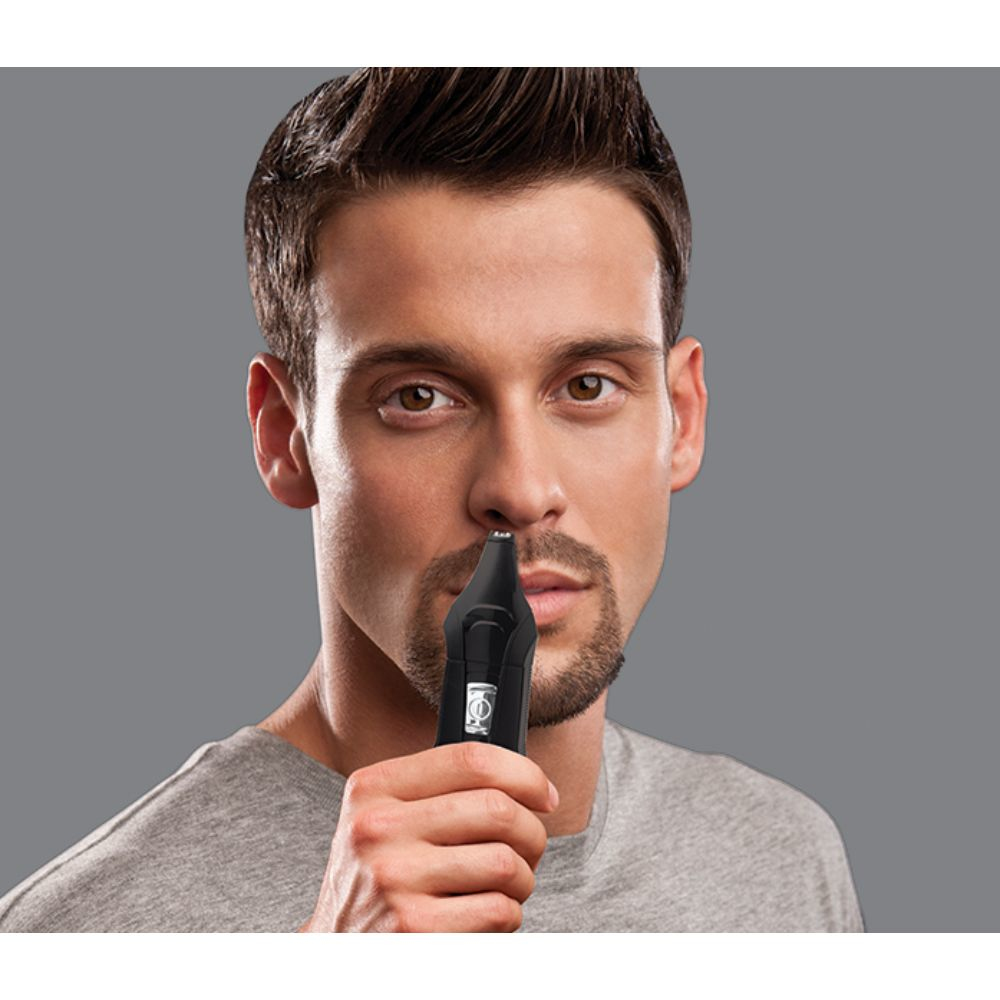 Mężczyzna używa czarnej maszynki do strzyżenia włosów w nosie; zbliżenie na twarz.