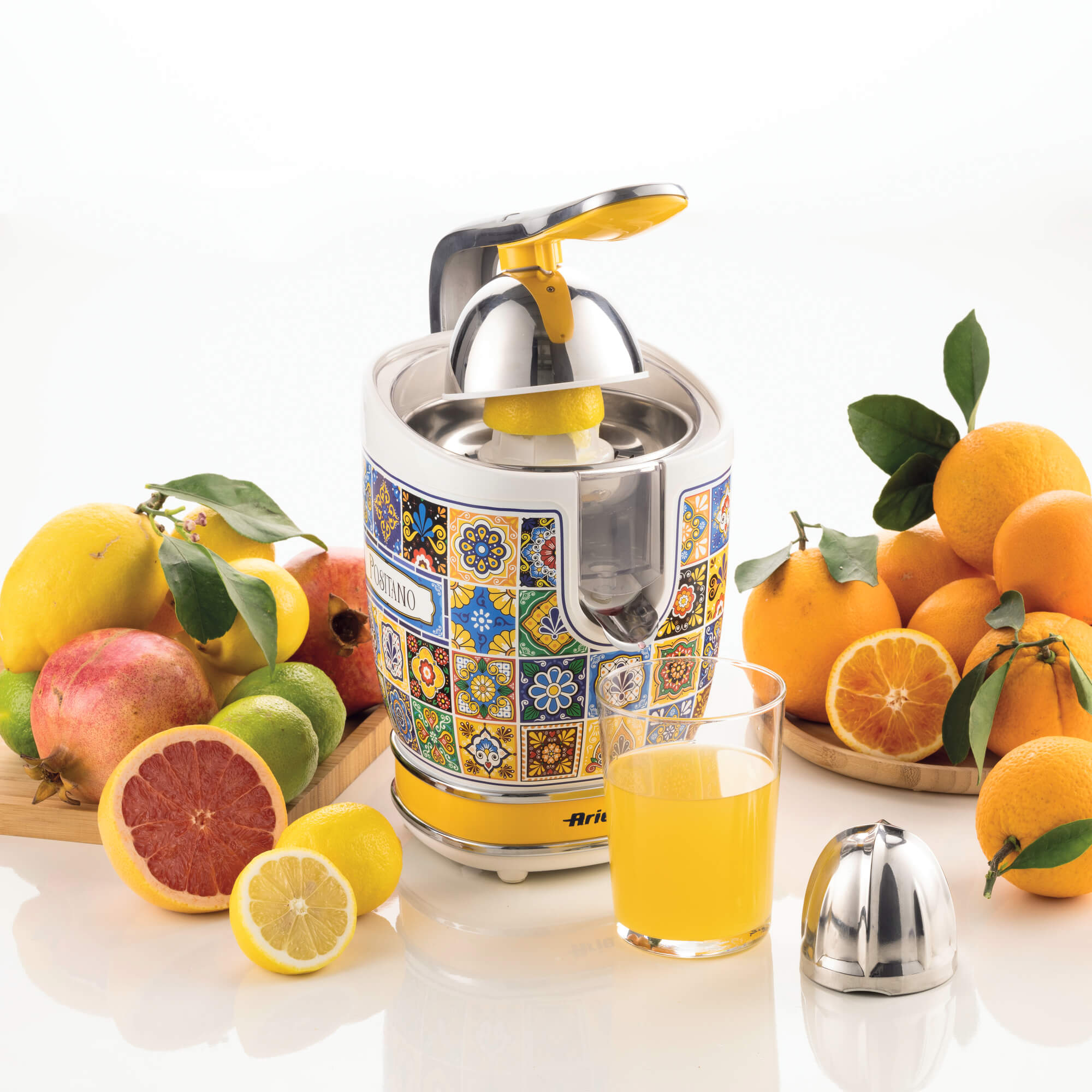 Entsafter mit Zitronen, Orangen und einem Glas Saft auf weißem Hintergrund.