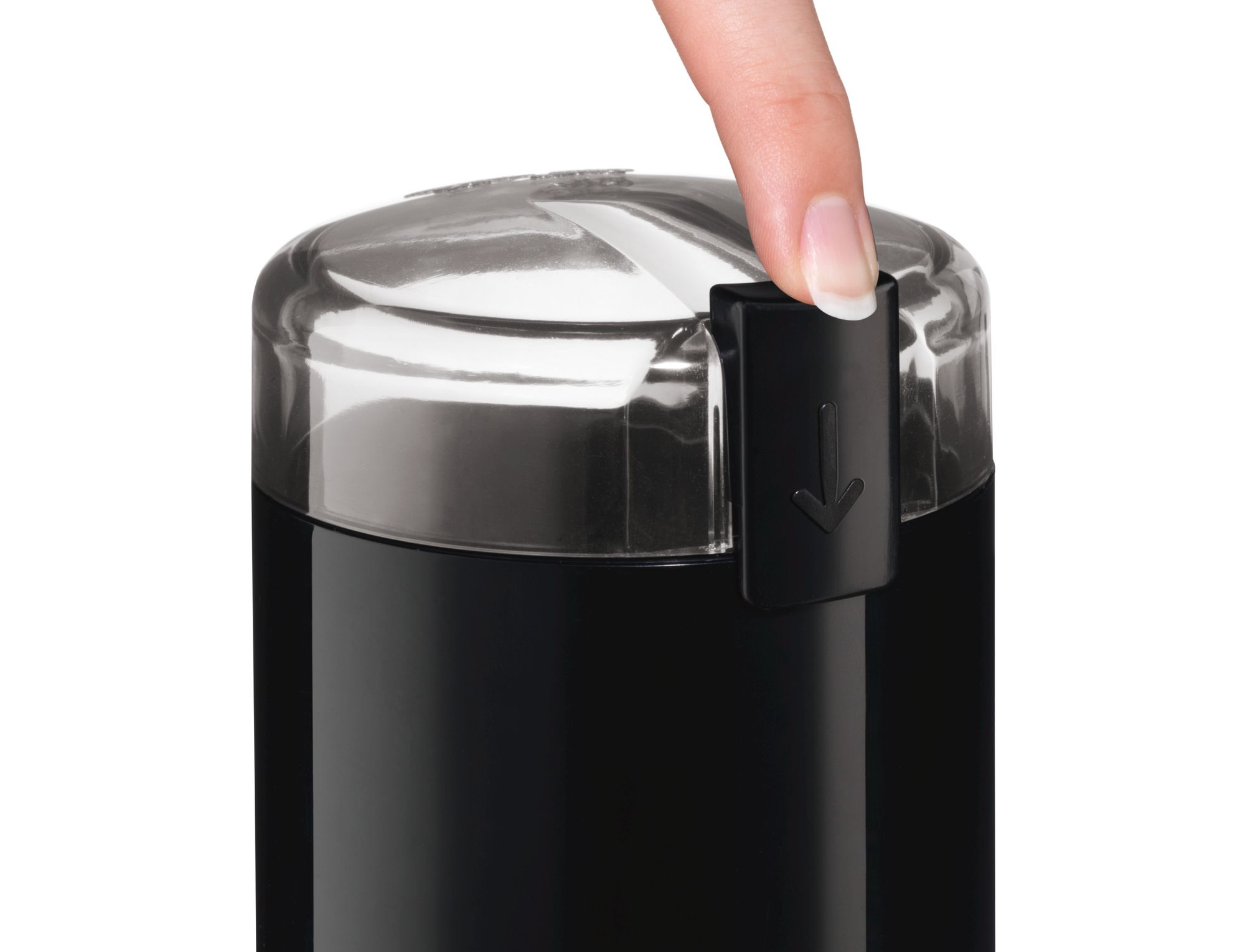 A black coffee grinder with a clear lid, a finger pressing the button.