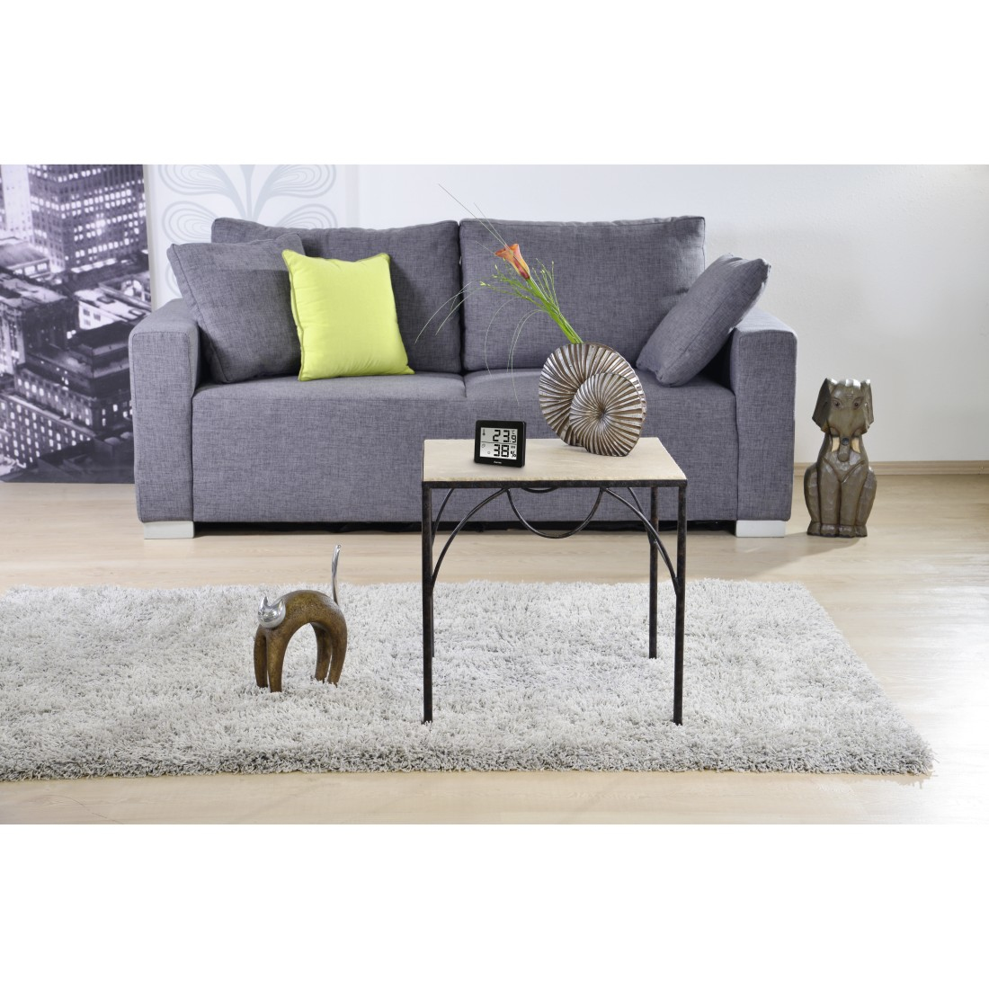 Salon z szarą sofą, stolikiem i elementami dekoracyjnymi. Widoczna jest statua kota.