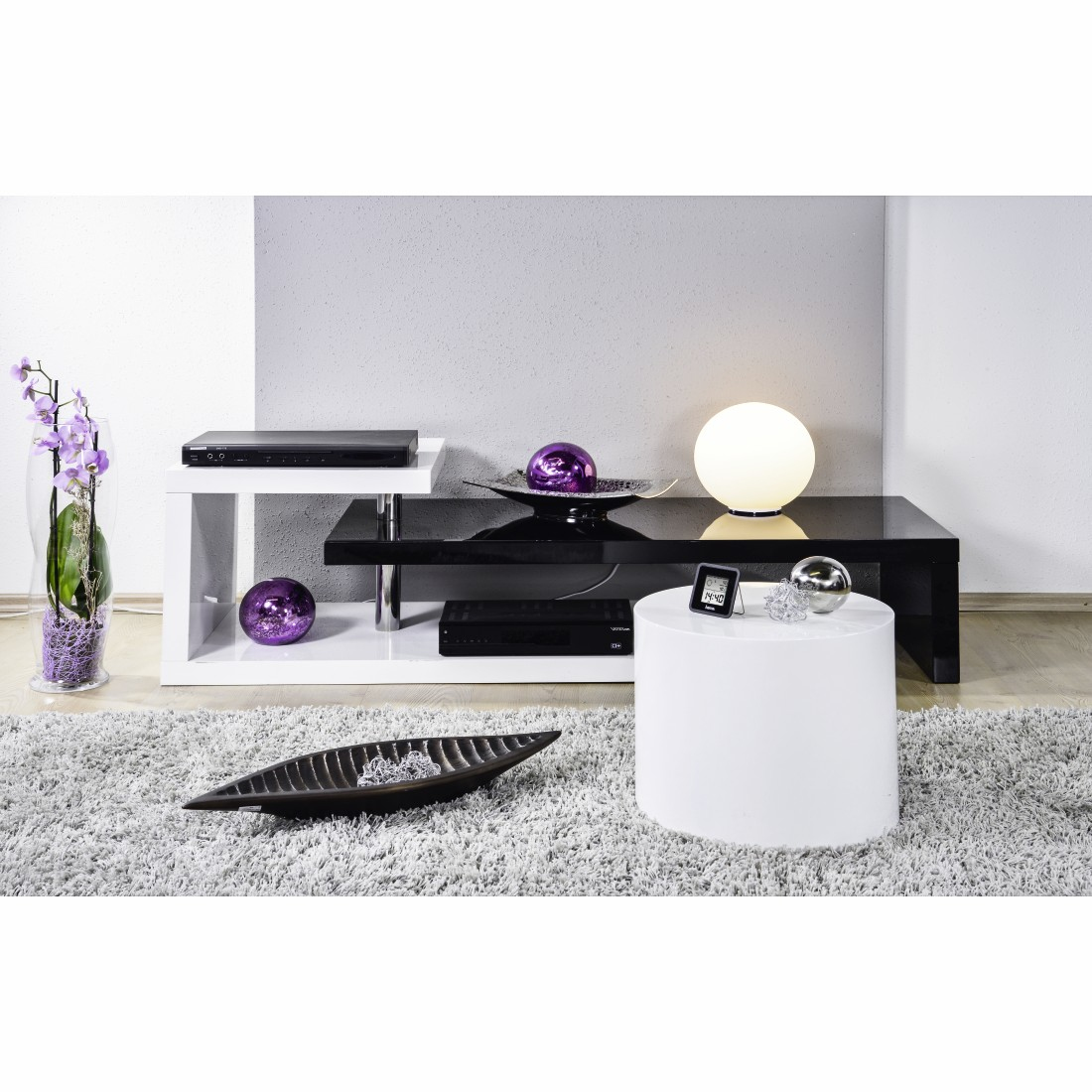 Nowoczesny wystrój salonu. Czarno-biała szafka RTV, okrągły stolik i dekoracje.