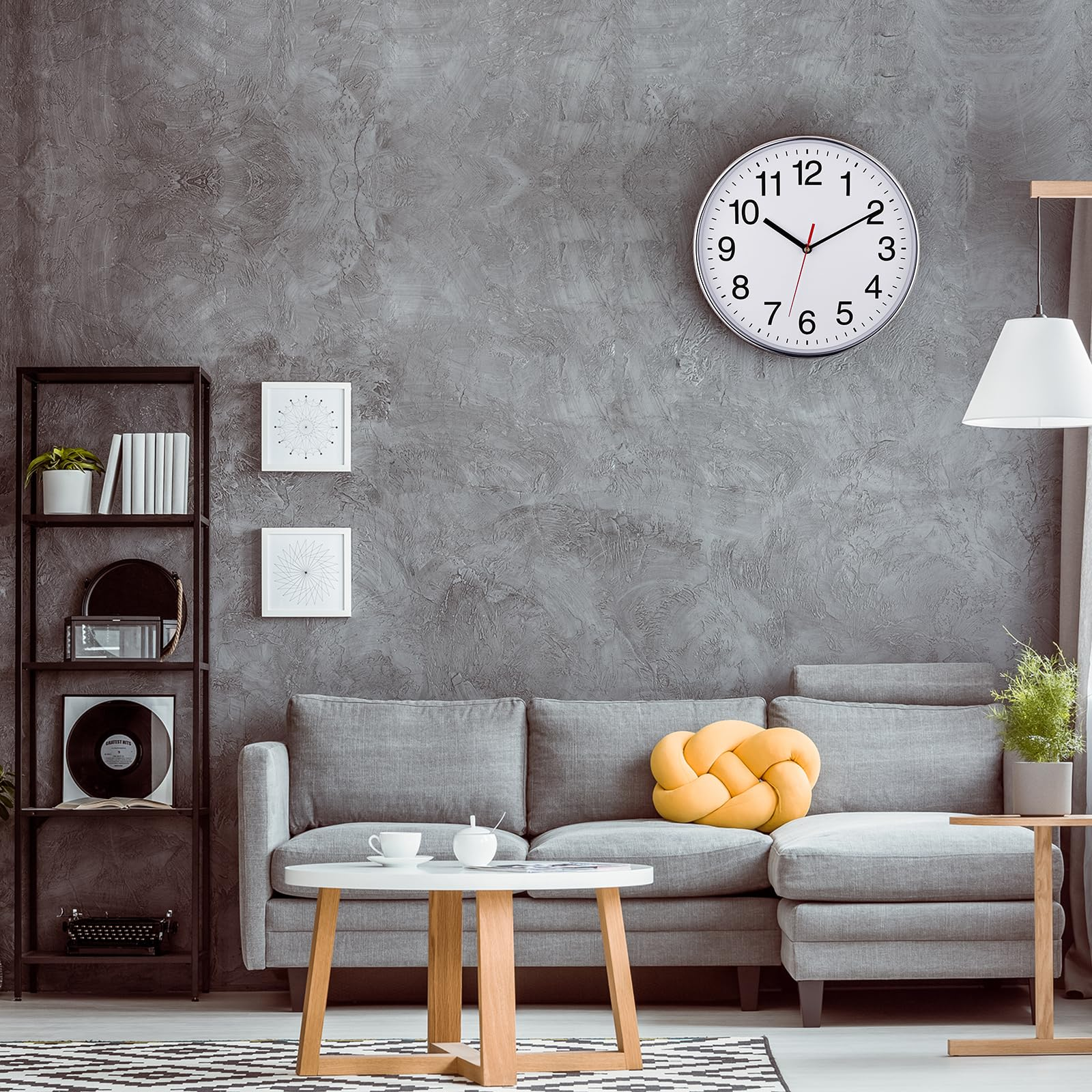Ein graues Wohnzimmer mit Sofa, Couchtisch, Uhr und Kunstwerken an einer strukturierten Wand.