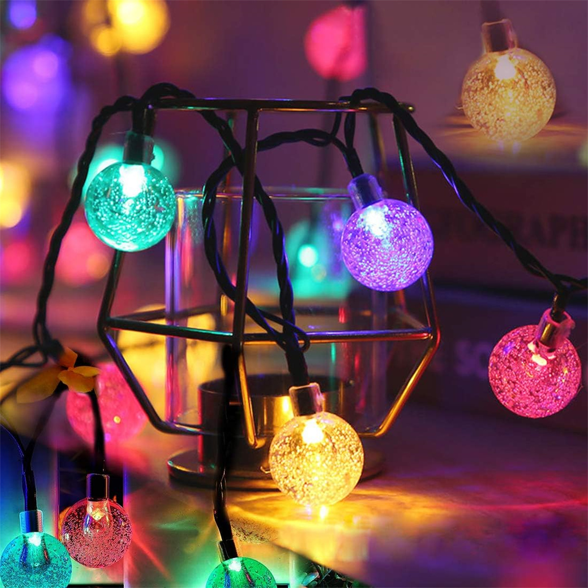 Lichterkette mit bunten, runden Glühbirnen vor einem Metallrahmen, mit dunklem Hintergrund.