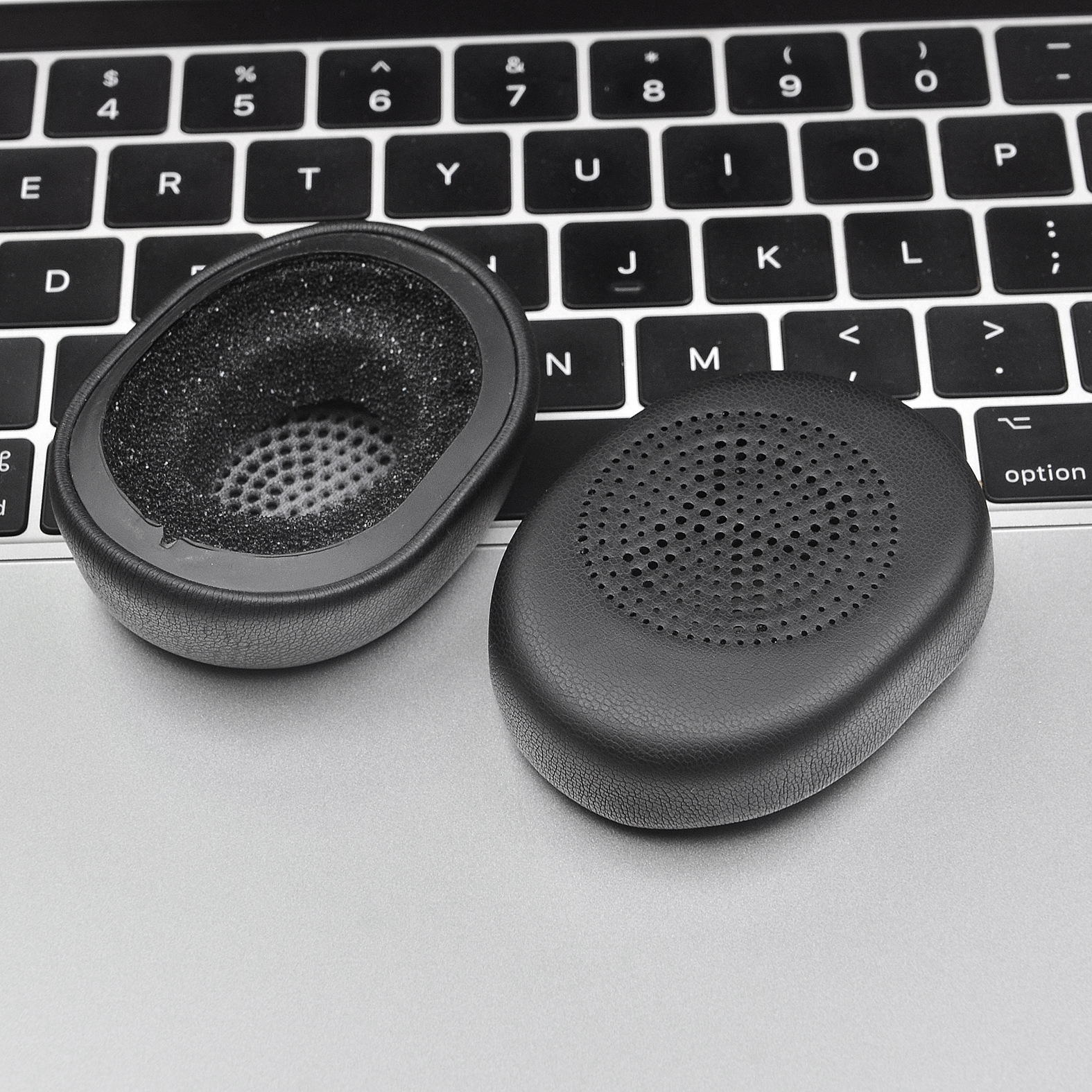 Cuscinetti auricolari su una tastiera del laptop. Un cuscinetto è aperto, mostrando la schiuma all'interno.