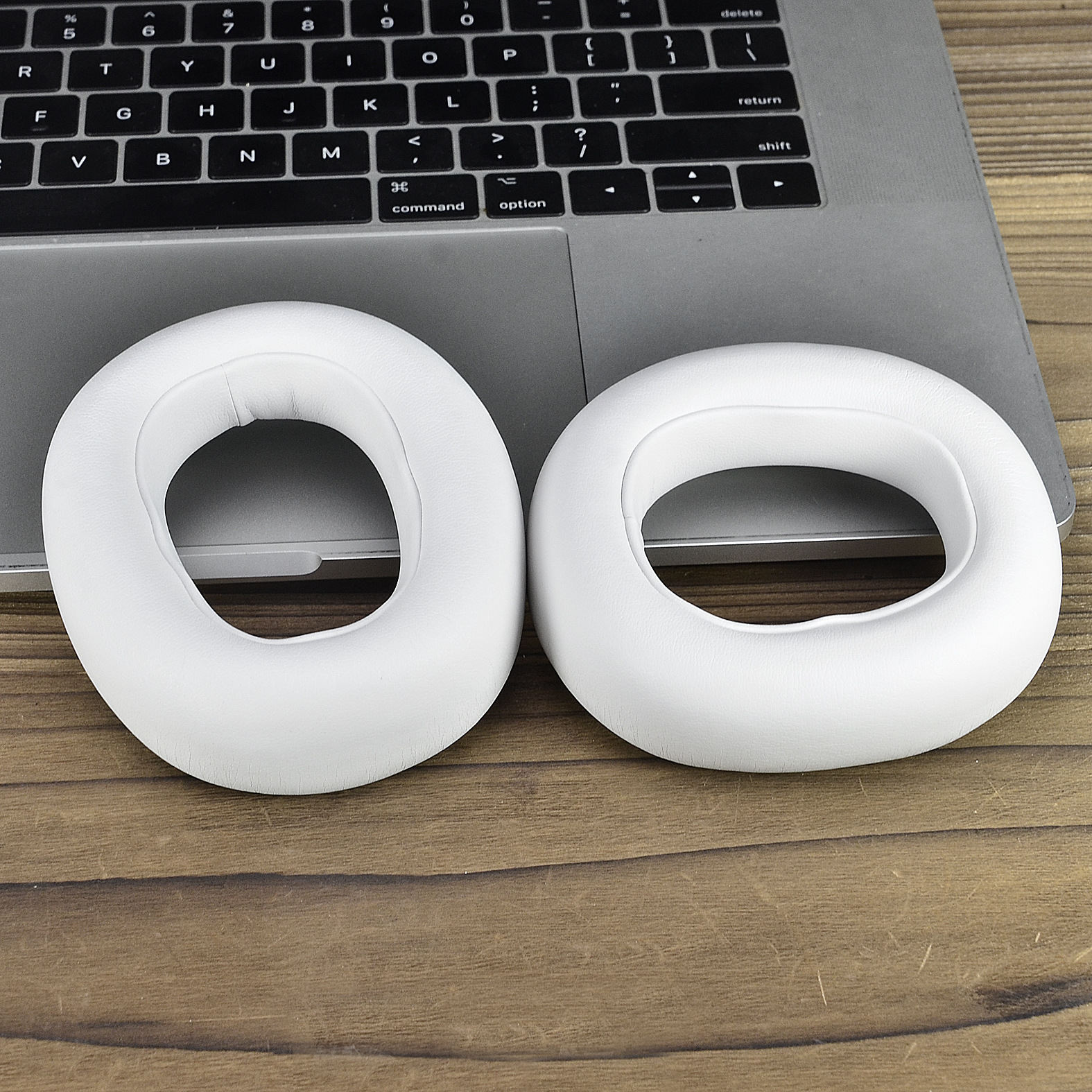 Due cuscinetti auricolari bianchi e circolari sulla tastiera di un laptop. I cuscinetti sono in materiale morbido.