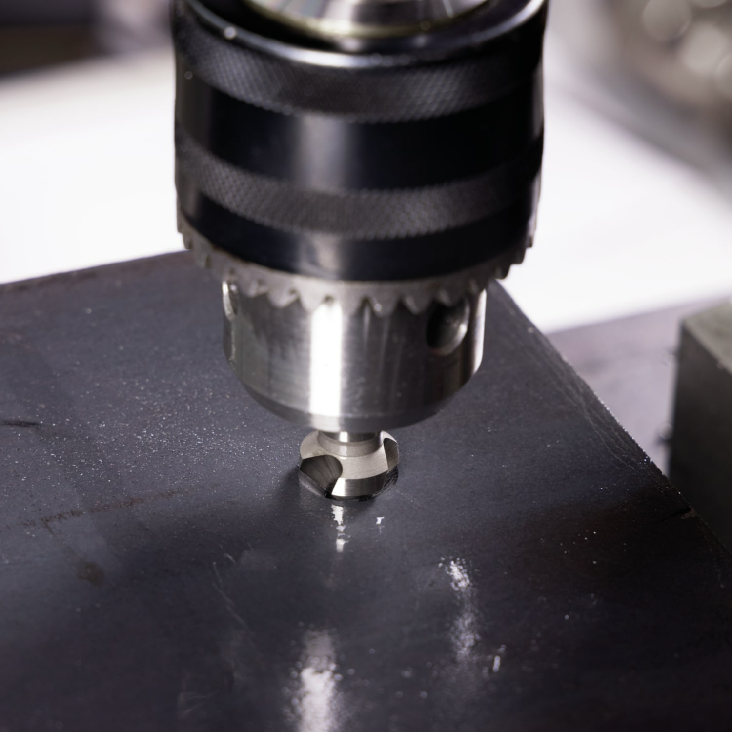 Wiertło wiercące otwór w metalowej powierzchni.