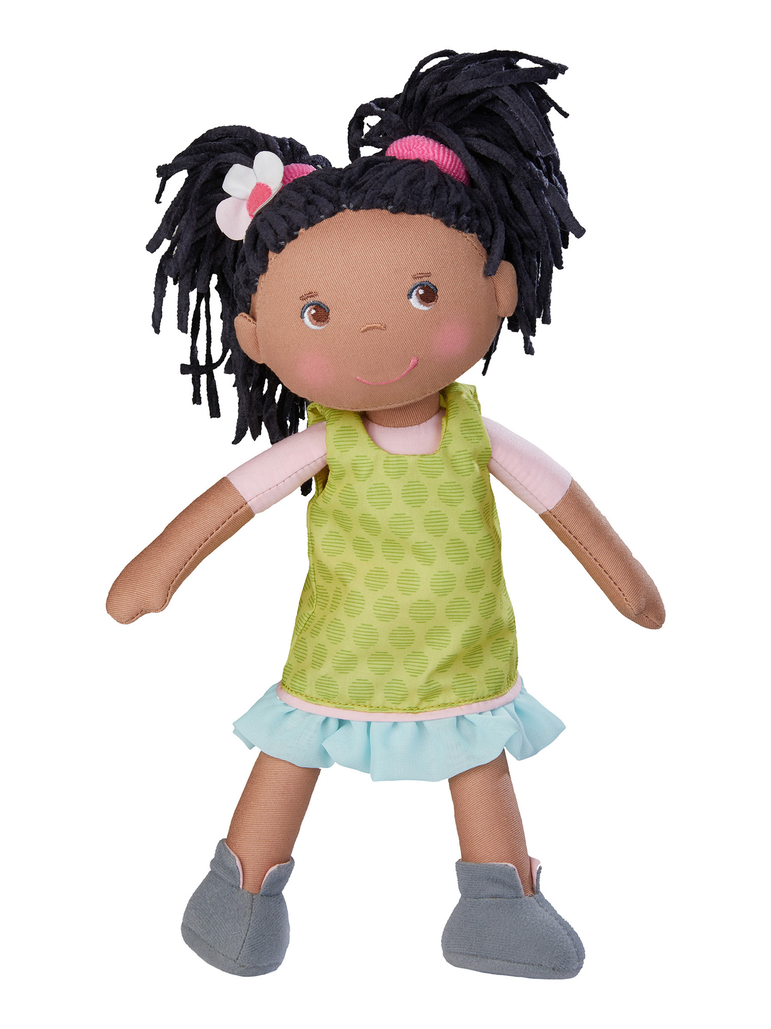 Eine Stoffpuppe mit schwarzen Haaren, einem rosa Hemd, einem grünen Kleid und grauen Schuhen.