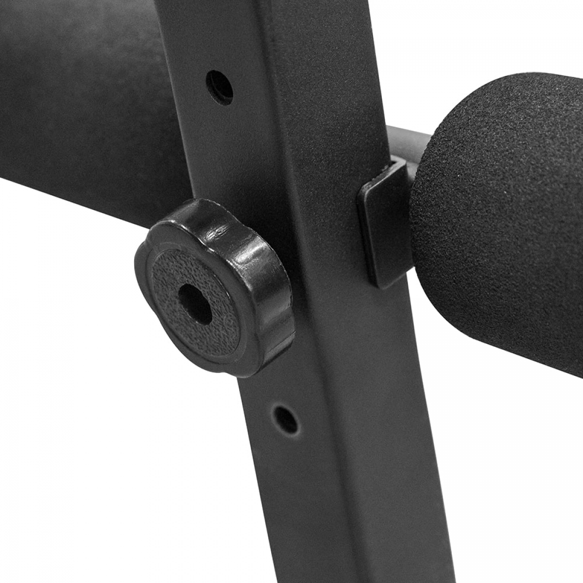 Close-up van een zwarte verstelknopp op een zwart metalen frame van een fitnessmachine.