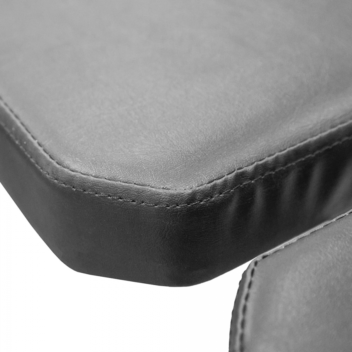 Close-up of a black bench surface with stitching detail. The bench is for gym use.