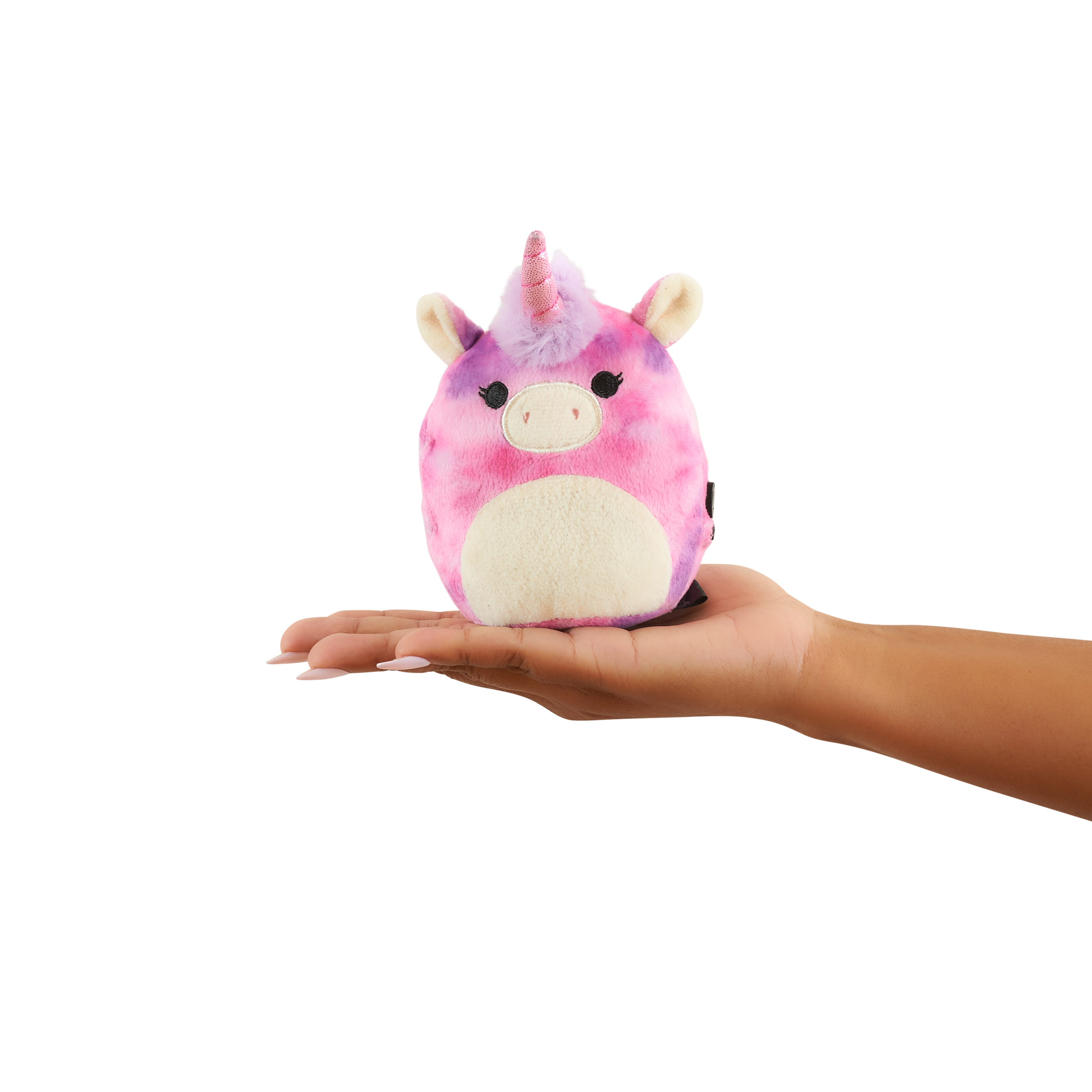 Hand die een roze, paarse en witte eenhoorn knuffel vasthoudt. Witte achtergrond.