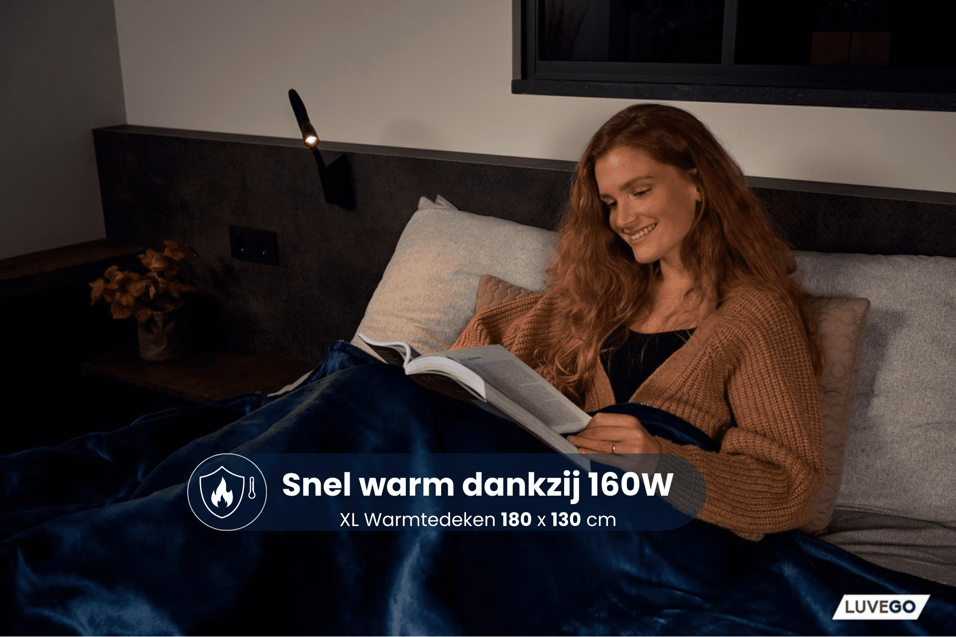Frau im Bett, liest Buch unter Lampe, mit Decke. Text: 'Snel warm dankzij 160W'.