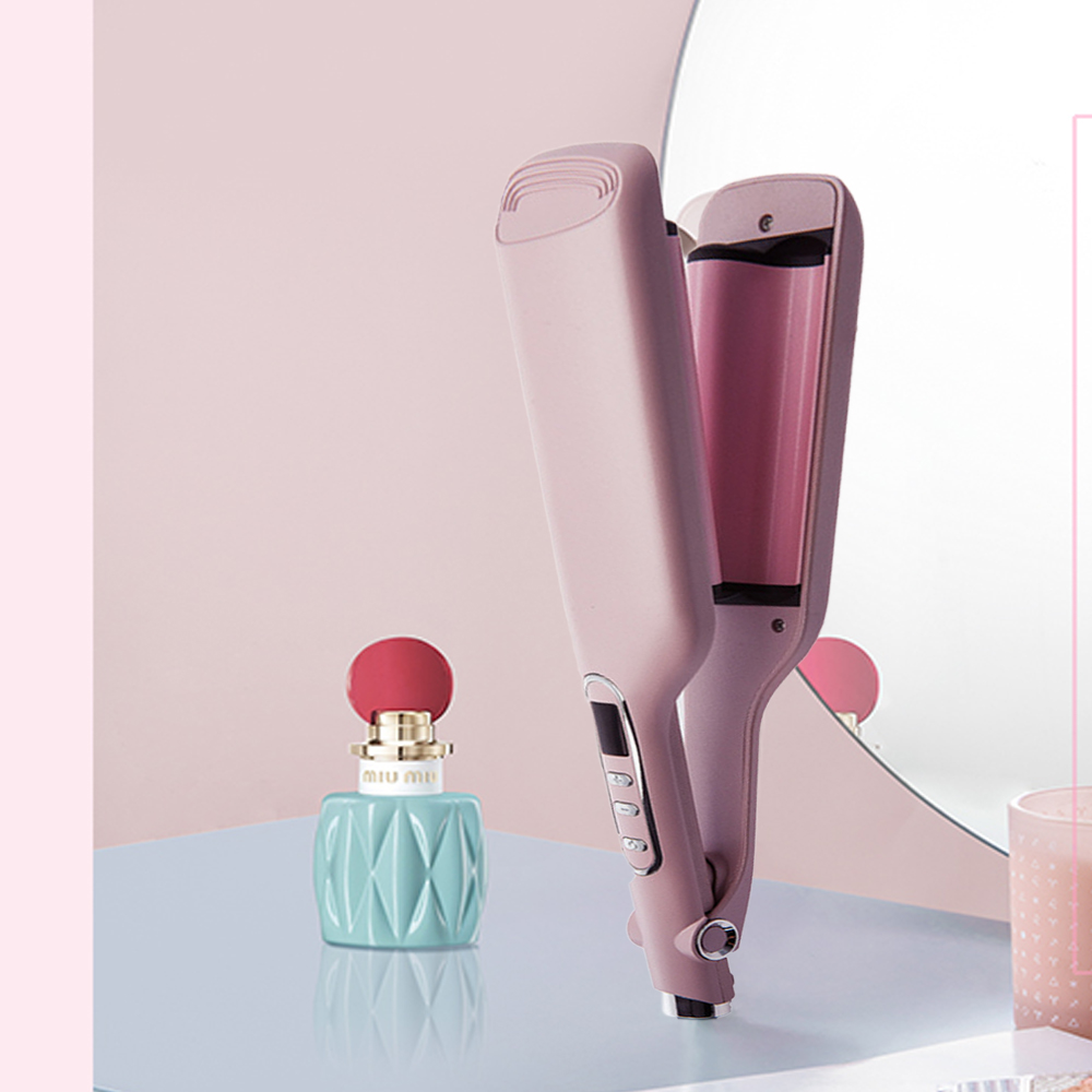 Pinker Haarglätter auf einem Tisch neben einer Parfümflasche und einer Kerze.