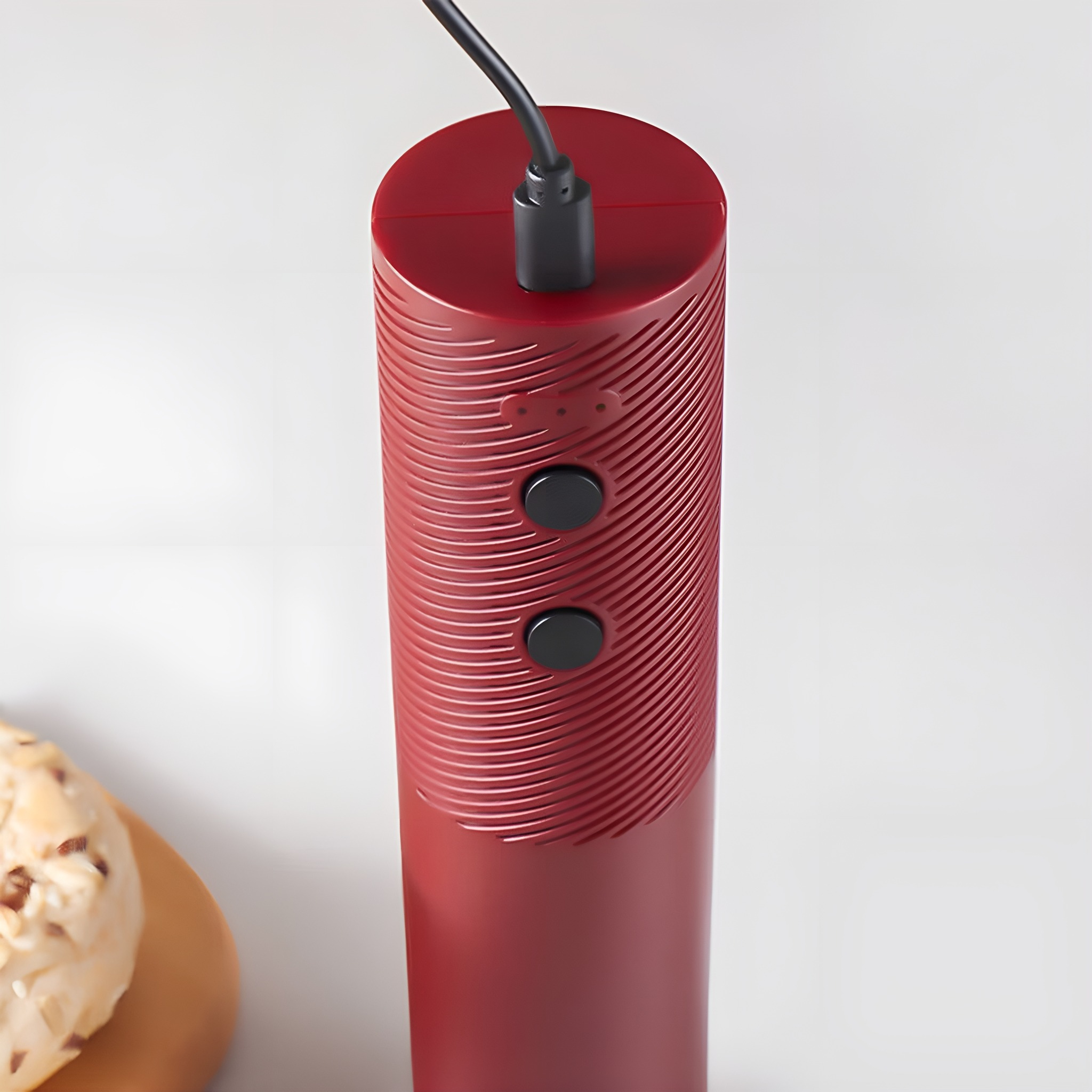 Ein rotes Ladegerät mit zwei schwarzen Knöpfen und einem eingesteckten schwarzen Kabel.