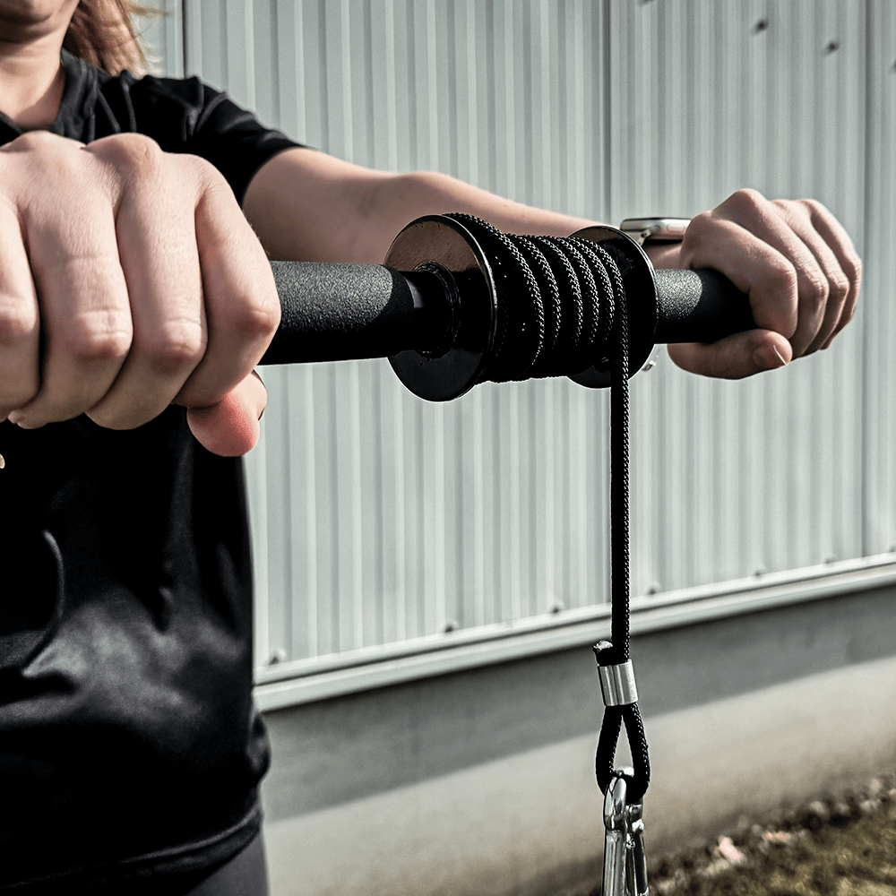 Les mains tiennent un rouleau de poignet noir avec une corde, sur un fond extérieur.