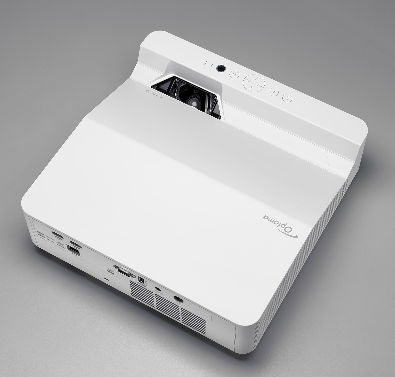 Biały projektor Optoma, widok z góry, widoczna górna strona, na szarej powierzchni.