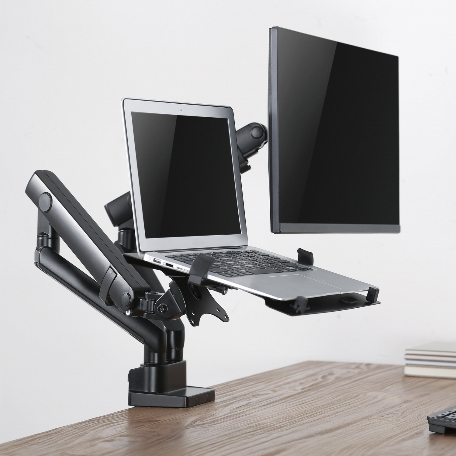 Un portátil y un monitor en un escritorio. El monitor montado en un brazo negro ajustable.