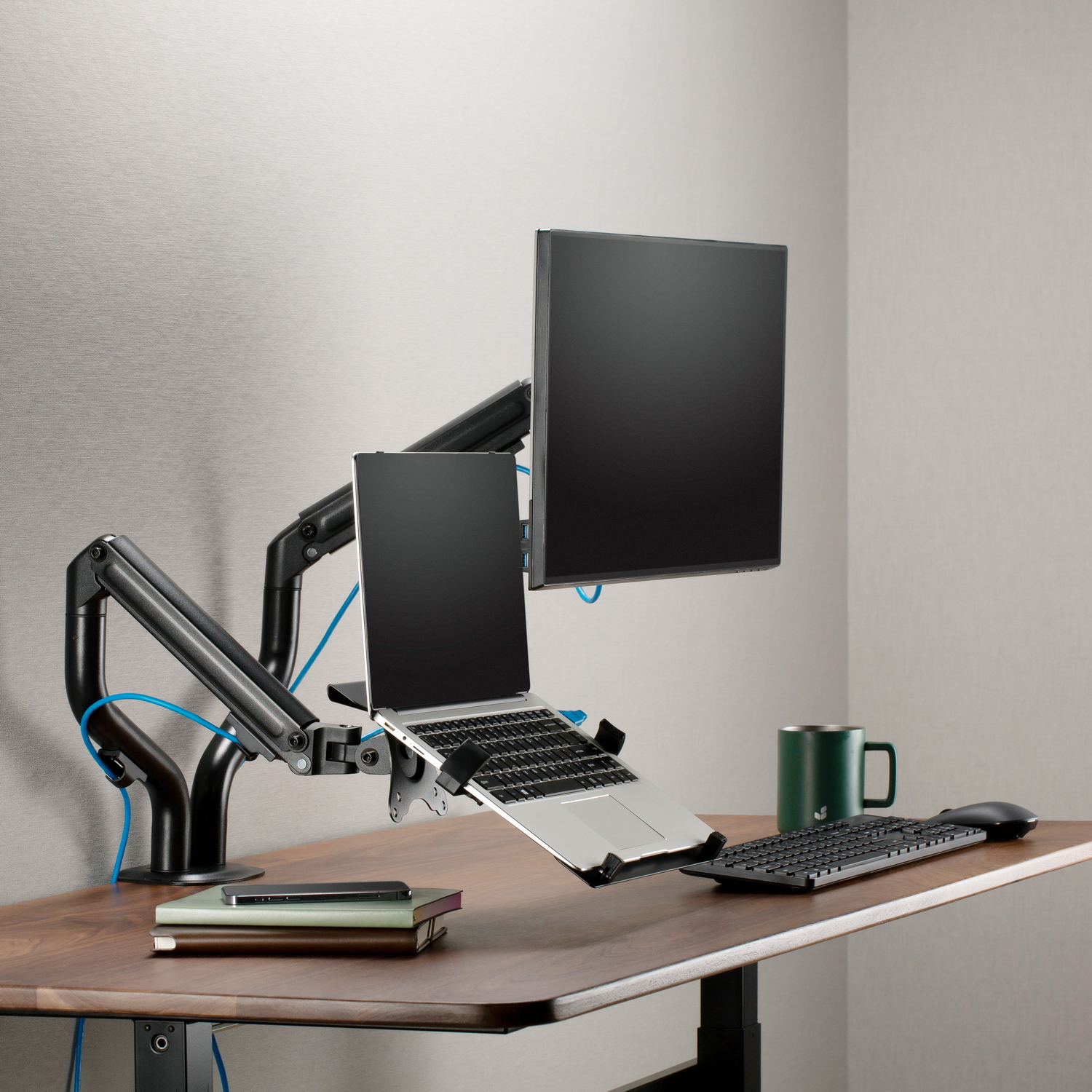 Konfiguracja monitora z laptopem, dwoma monitorami i kubkiem na biurku. Czarne i szare kolory.