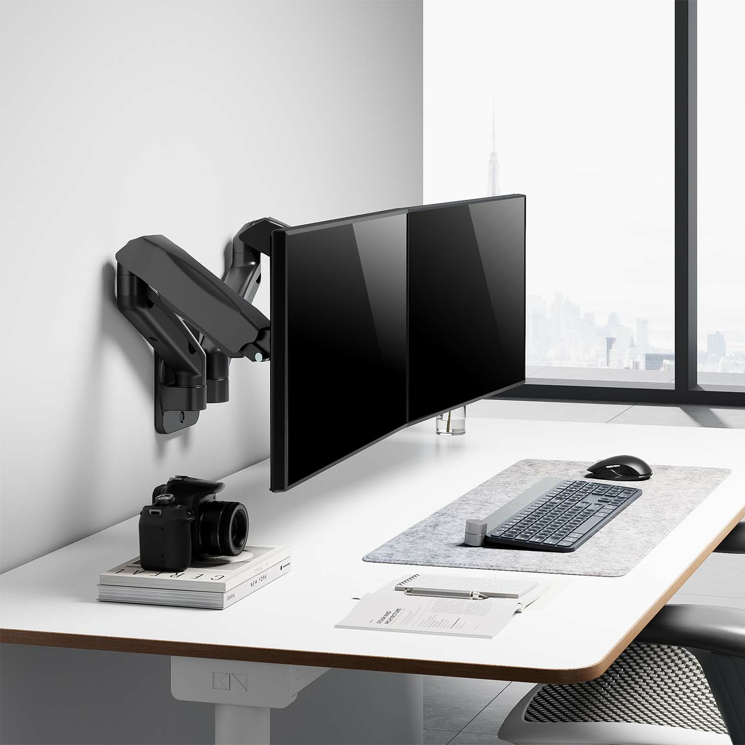 Dos monitores montados en un soporte de pared. Una cámara y teclado en el escritorio debajo.