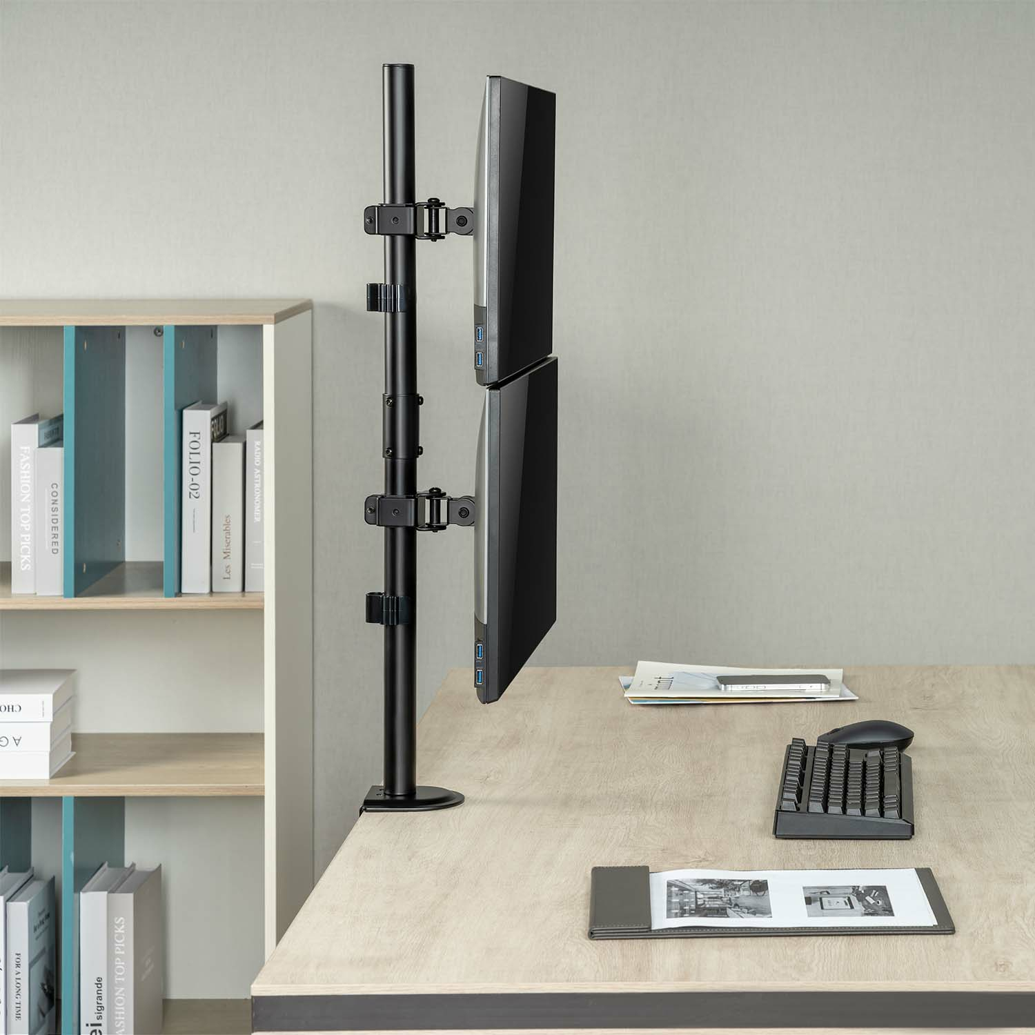 Monitores de computadora dobles montados en un soporte sobre un escritorio, con teclado y bloc de notas.