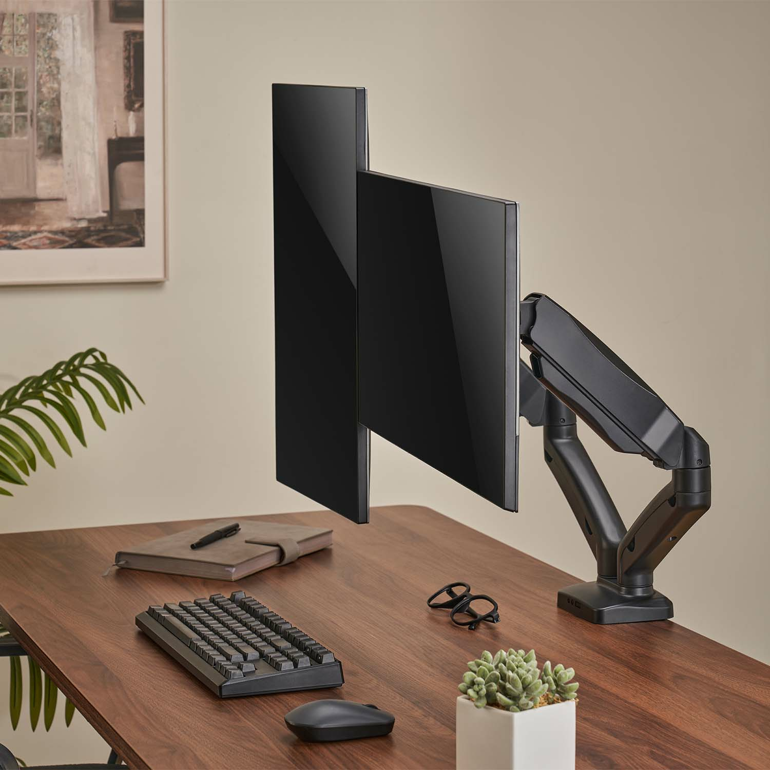 Un monitor negro en un escritorio, con teclado, ratón y accesorios. El fondo muestra una pared y una ventana.
