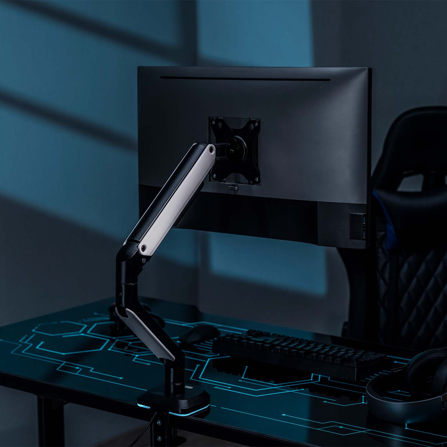 Configuración de brazo y monitor en un escritorio con fondo azul oscuro. El monitor está encendido.