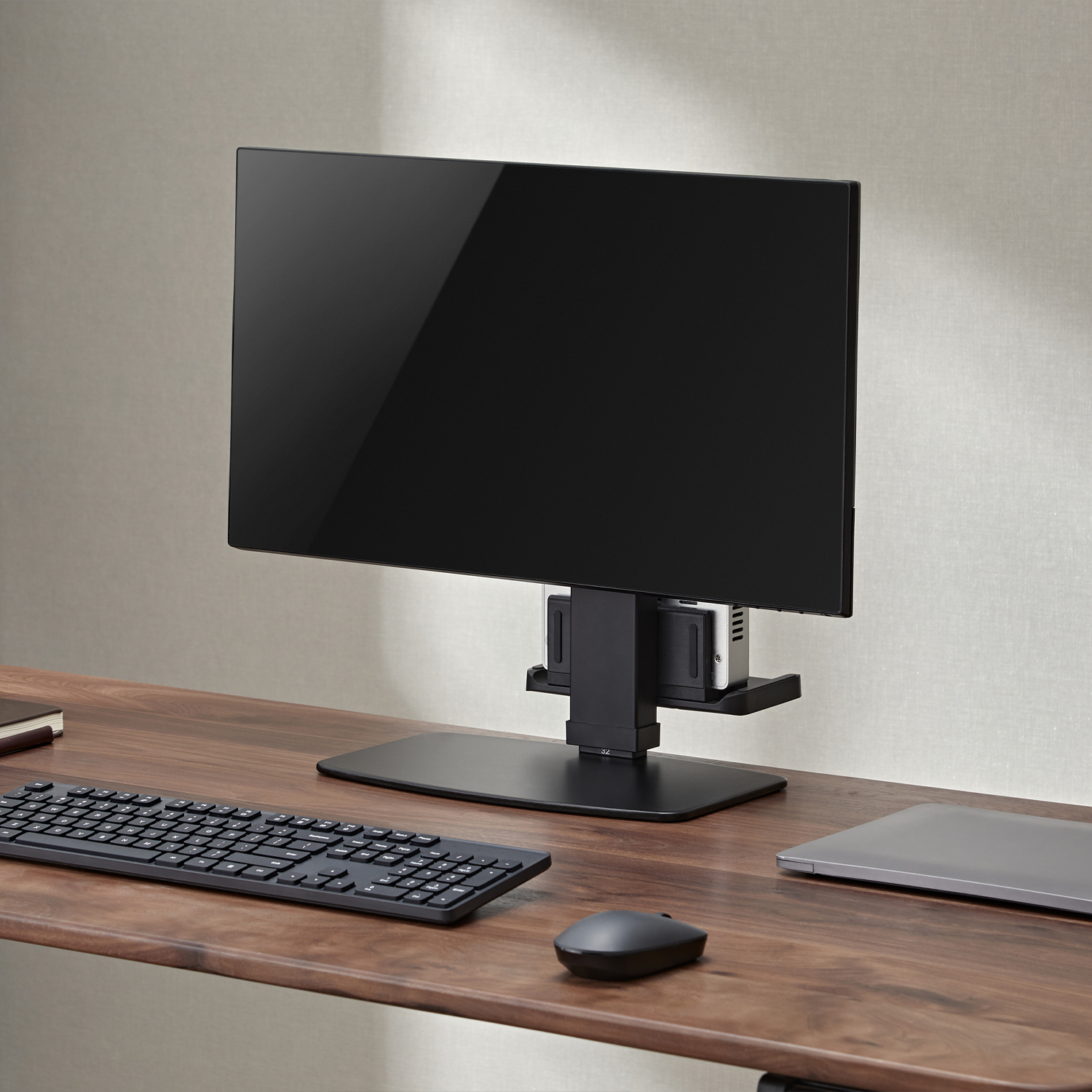 Monitor en una configuración de escritorio. Monitor negro, teclado y ratón visibles. Madera.