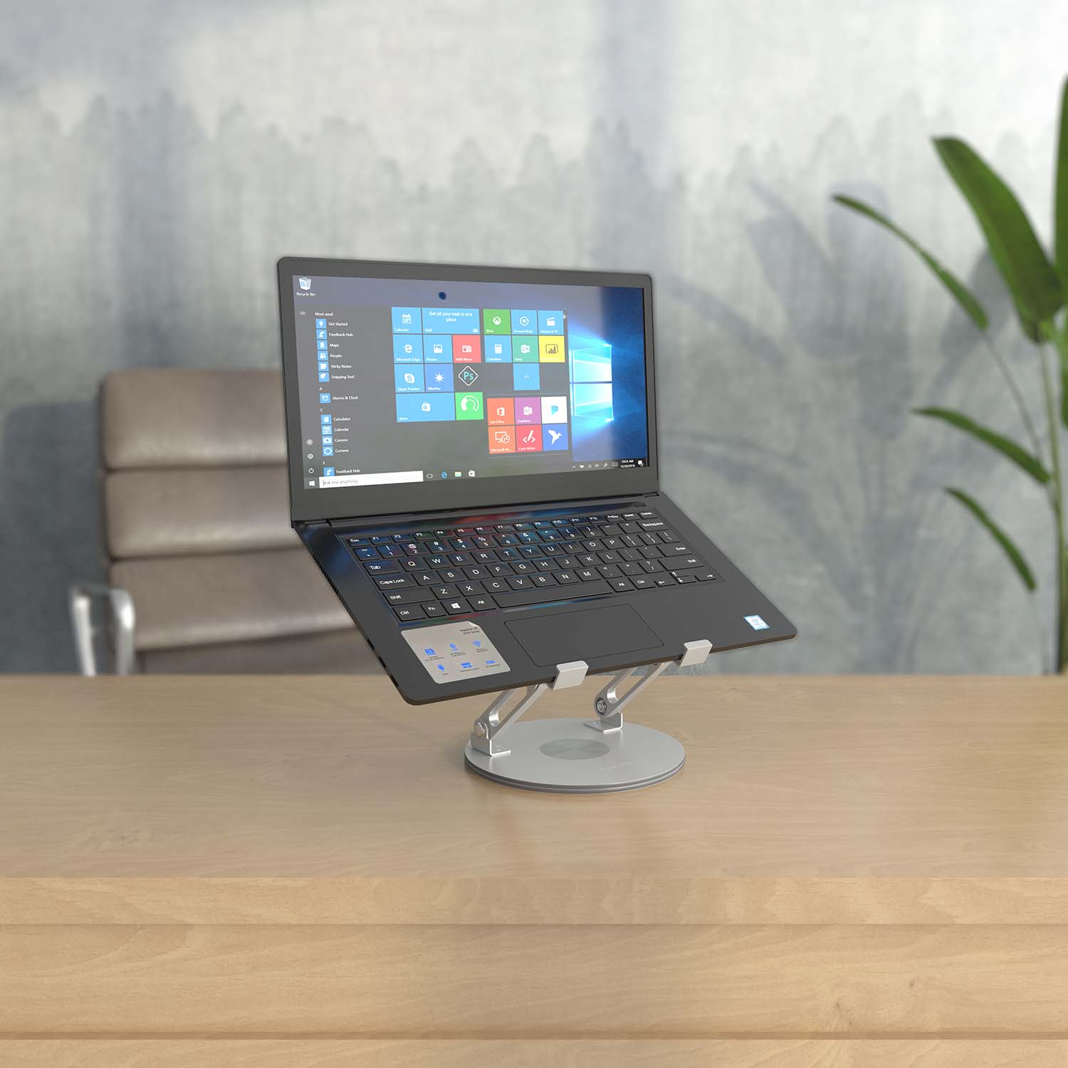 Een laptop op een standaard, op een houten bureau. Er is een stoel en een plant op de achtergrond.